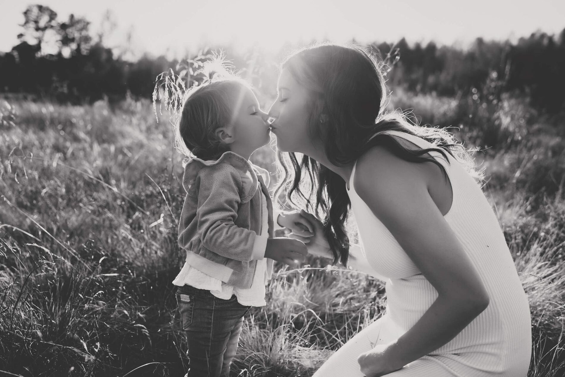 Heart-warming black and white photo of mom kissing her young daughter