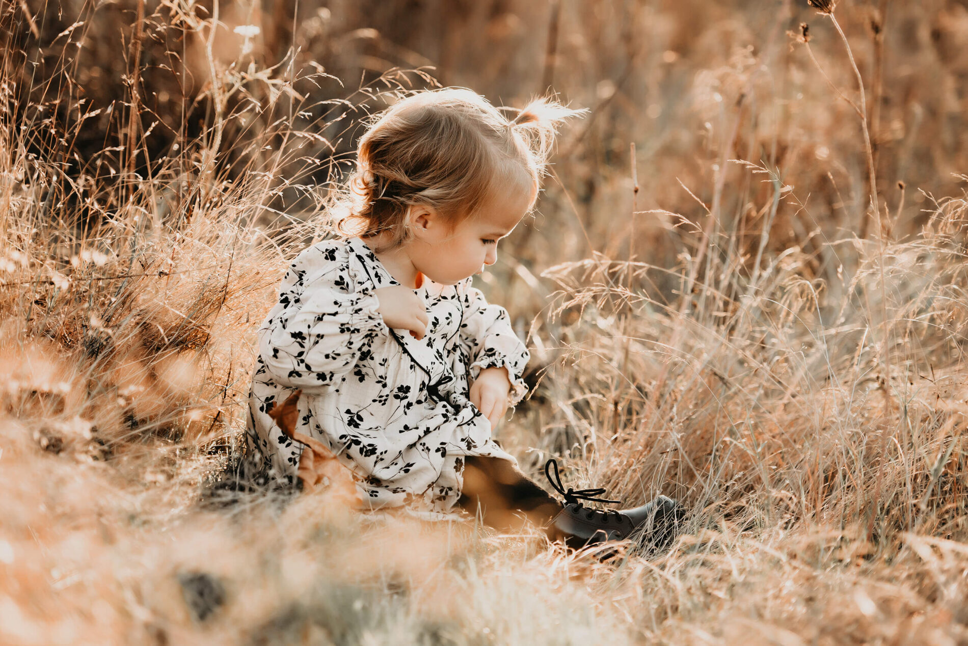 A young girl sitting in a beautiful field of tall grass
