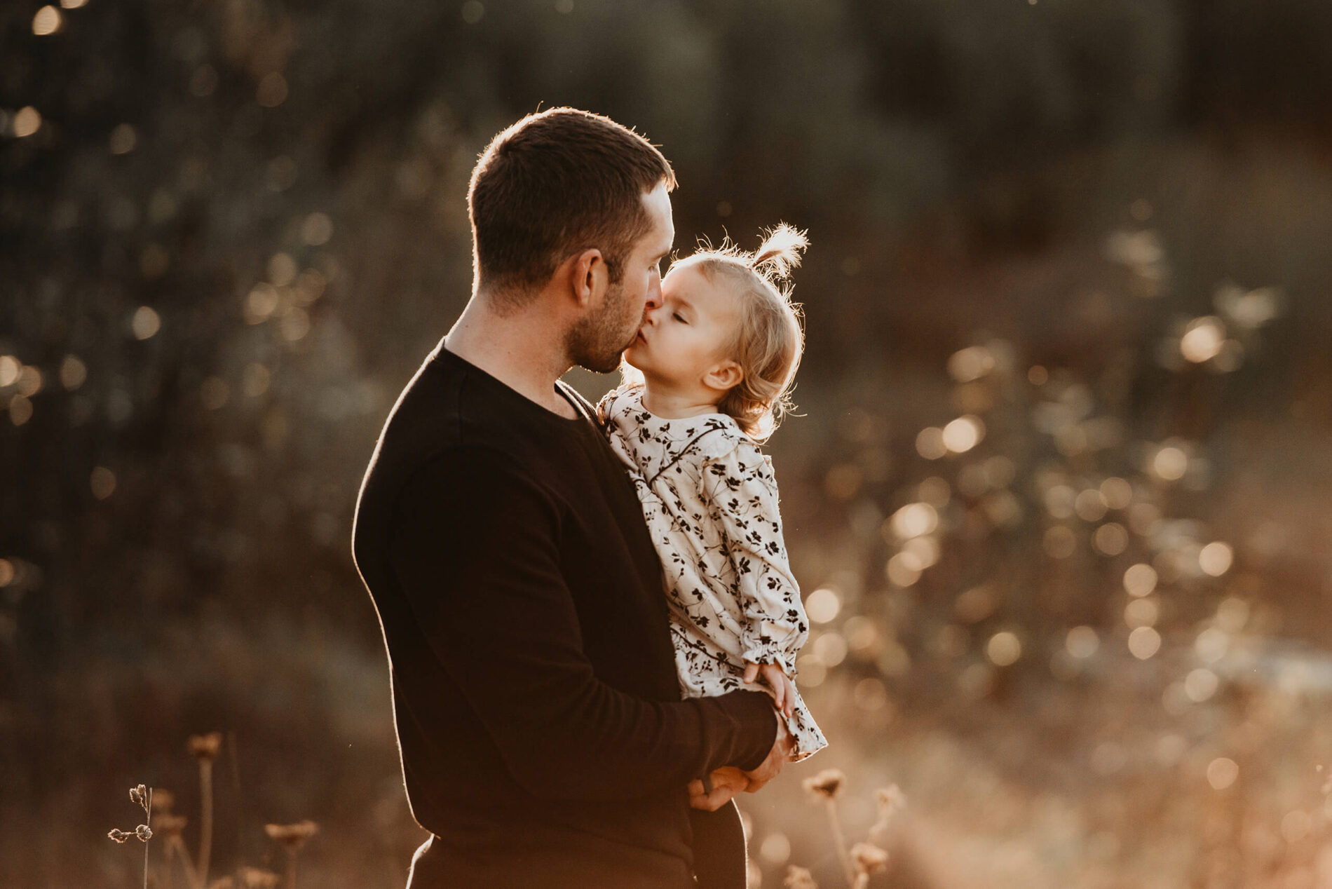 Family photo shoot in Seattle area, a cute family portrait of a dad holding his young girl in his hands and lovingly kissing her