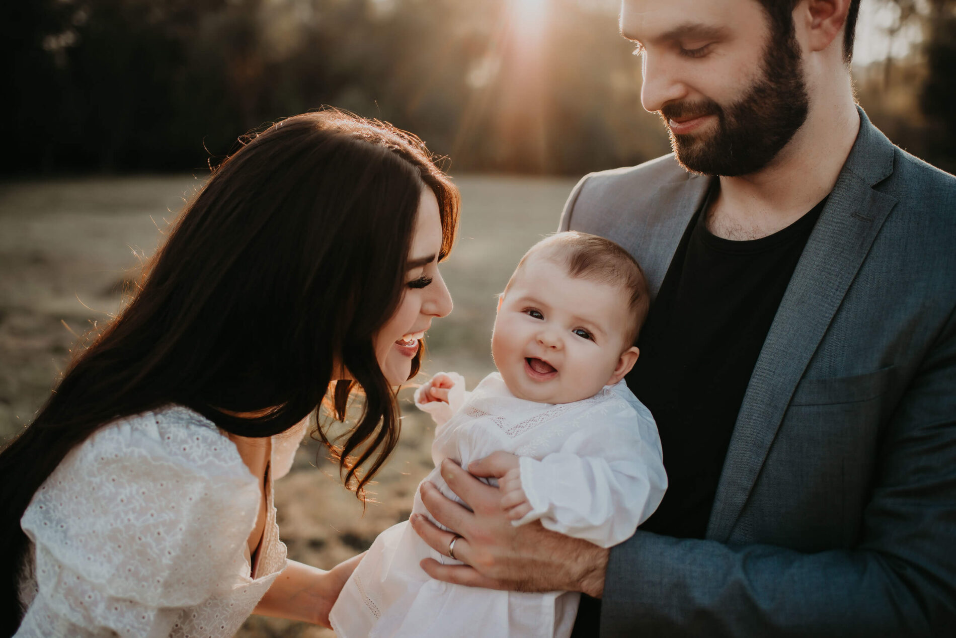 Mom playing with her toddler daughter, who is being held by dad