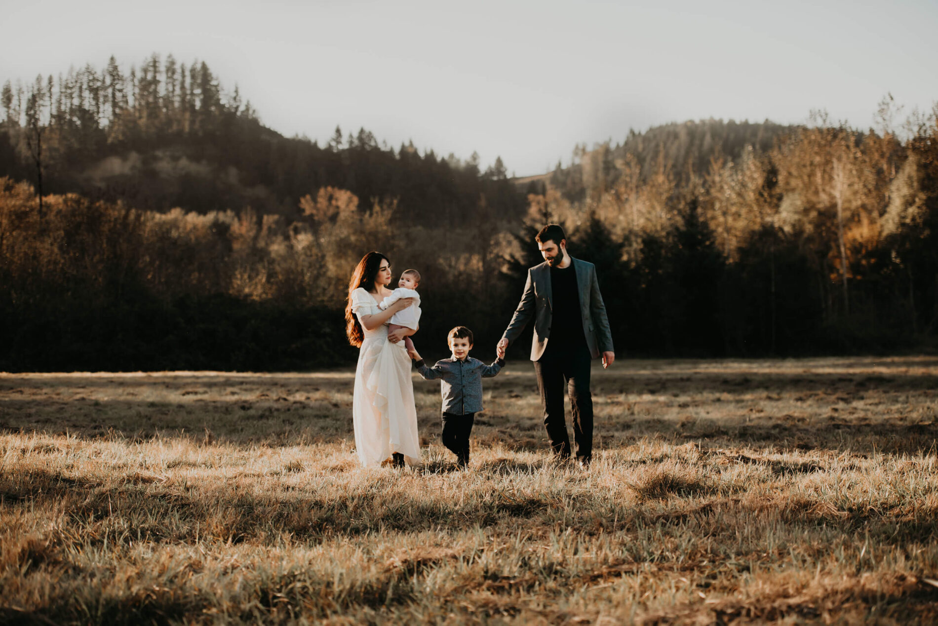 A family walking through a backlit field during sunset