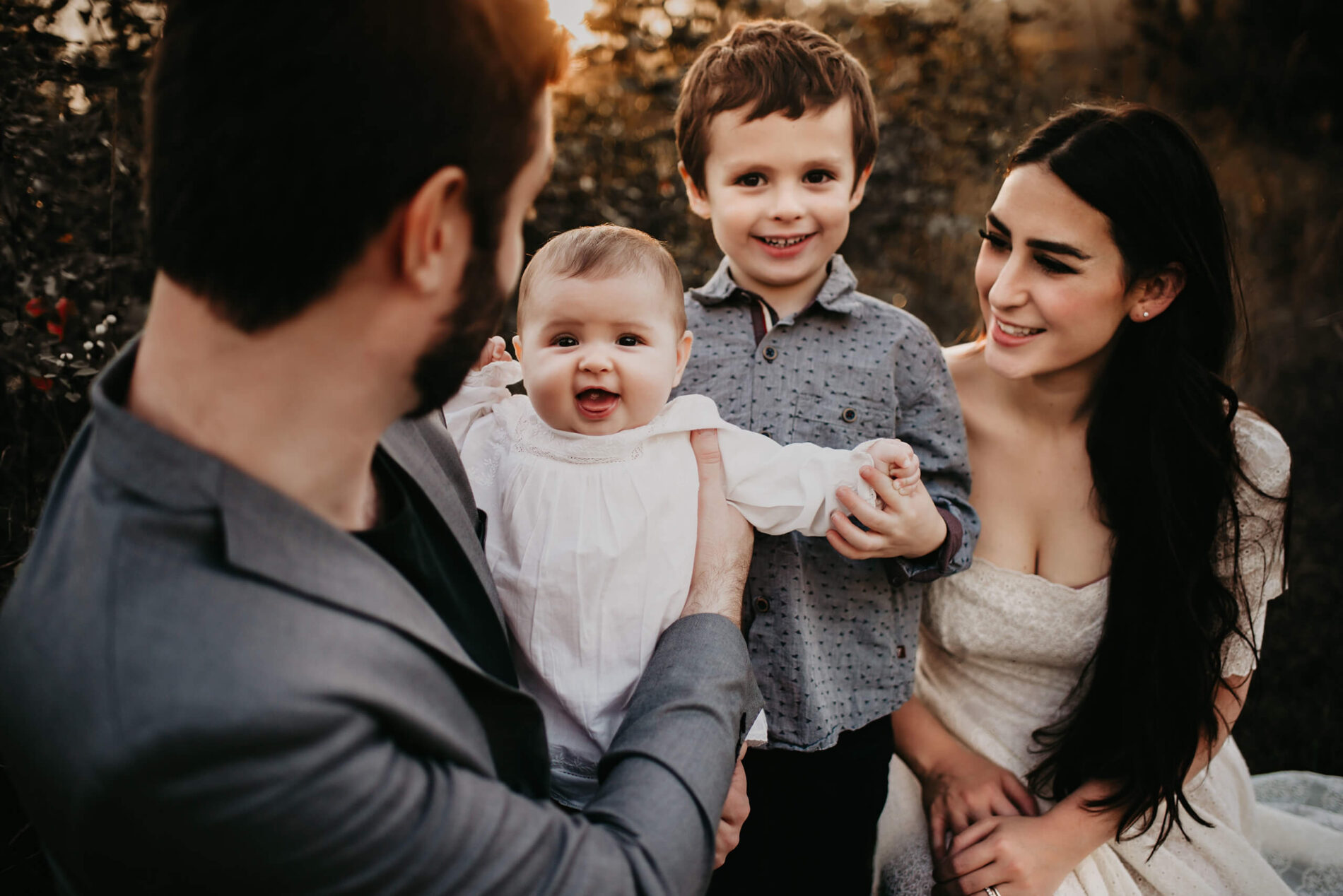 A close-up on faces of mom, dad, toddler daughter, and son, everyone is happy and joyous