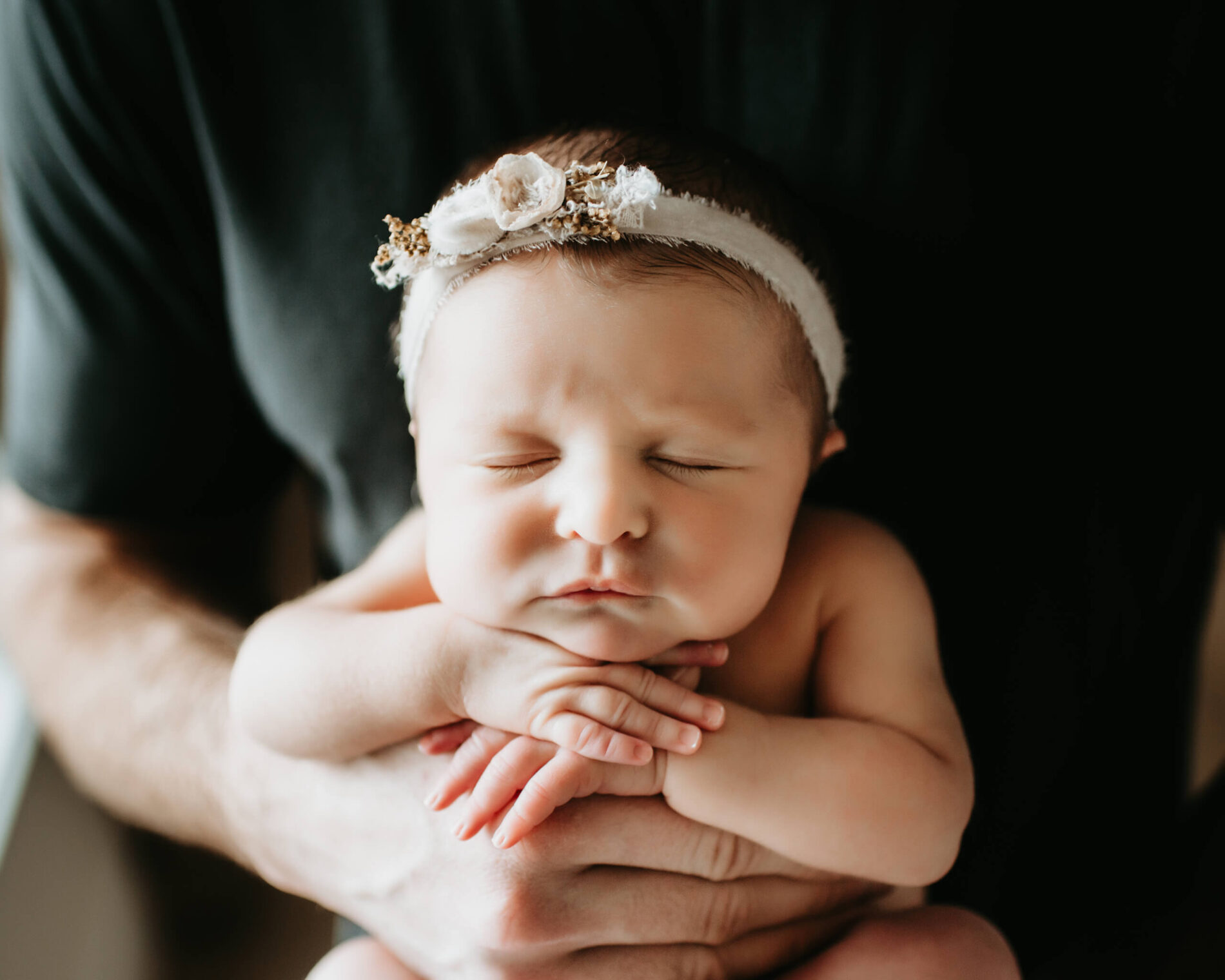 A close-up on a newborn girl sleeping in daddy's arms