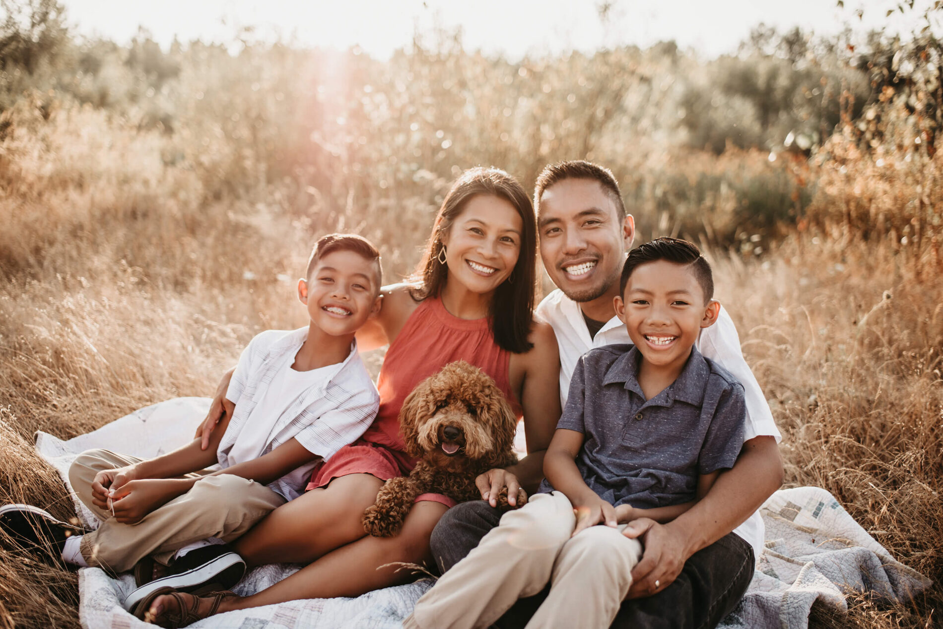Mom, dad, two sons, and their dog, hugging and posing for a family portrait