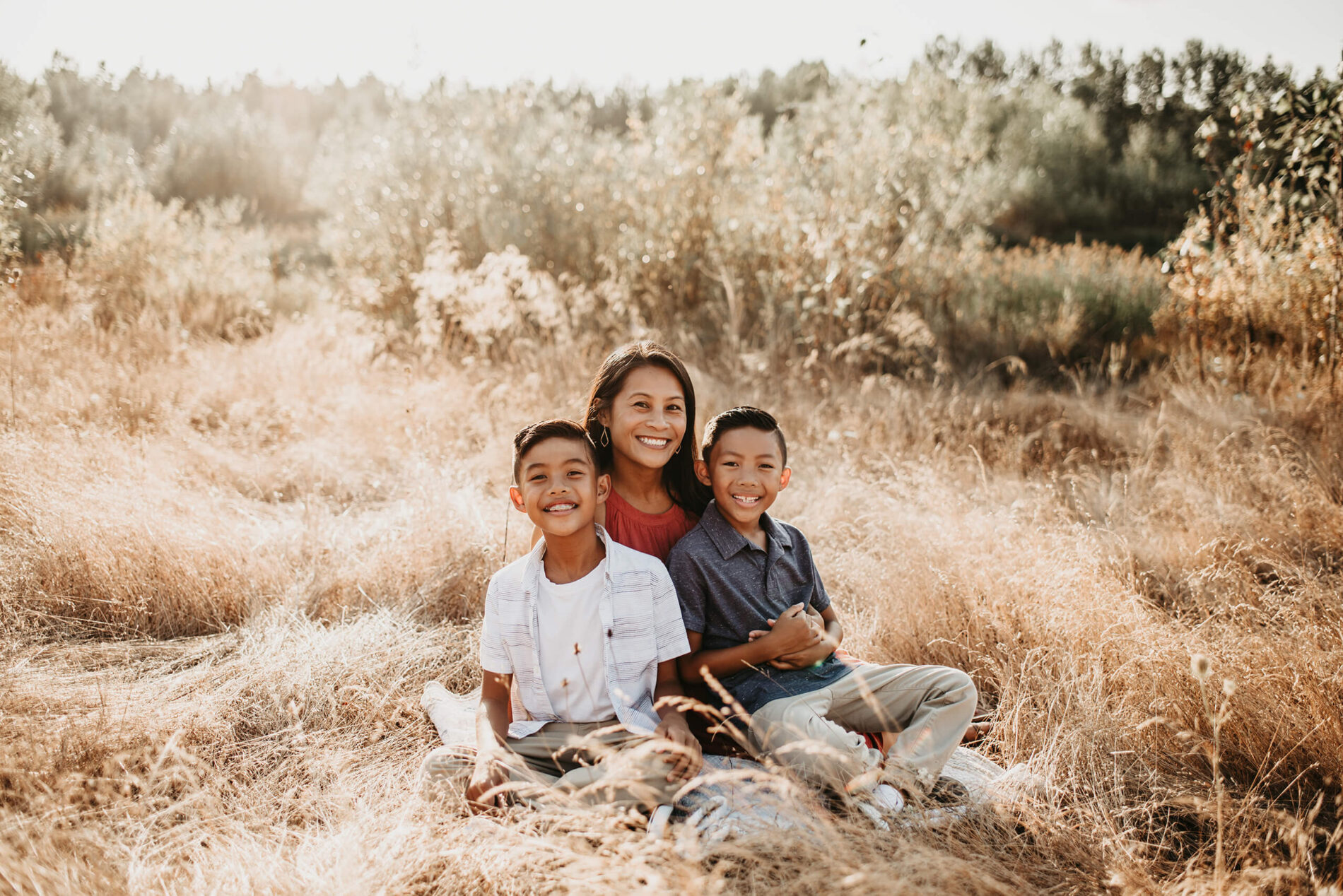 Mom posing with two sons, sitting in a field