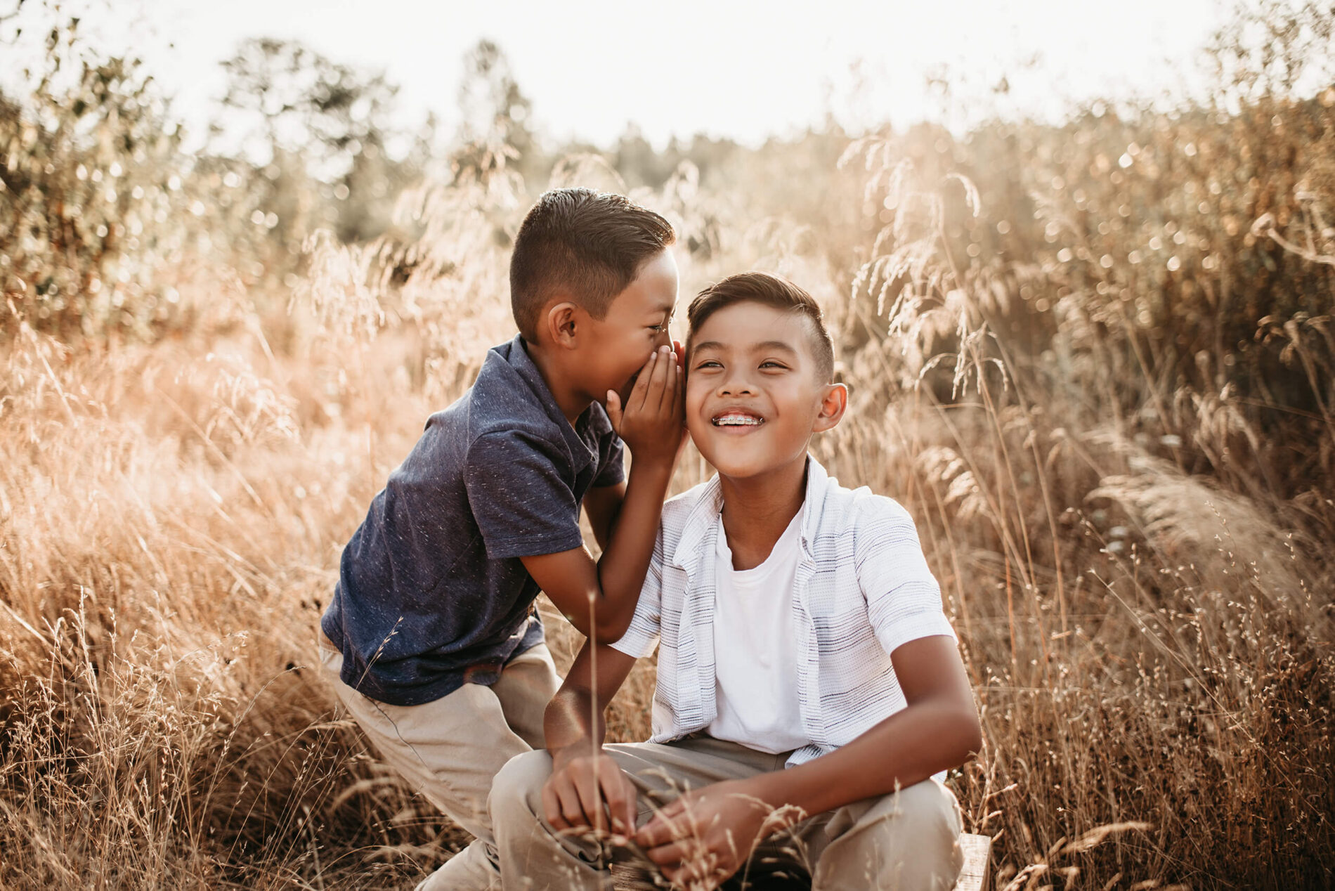 Two brothers having fun, one of them is whispering into the ear of another