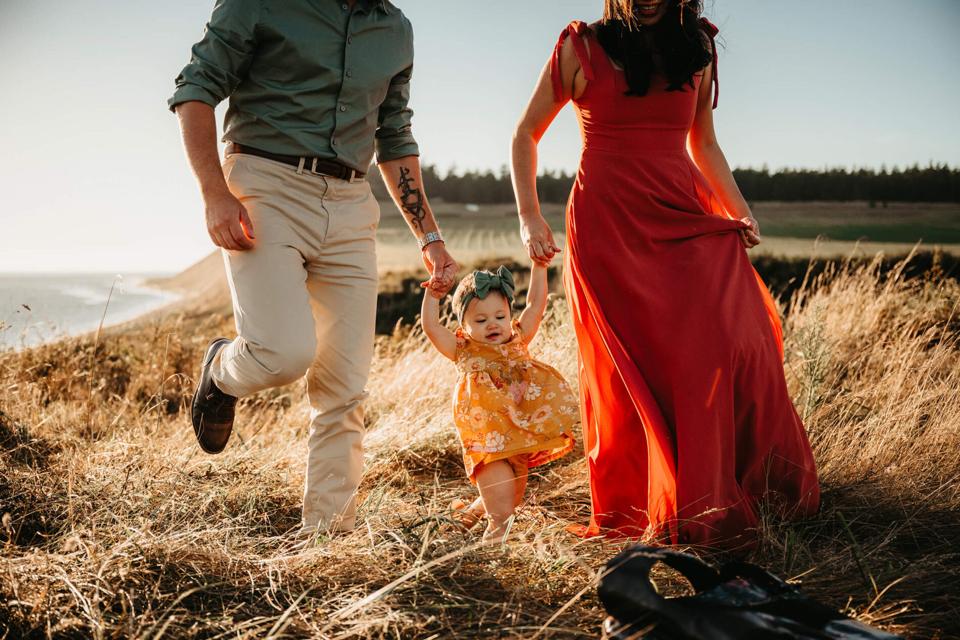 Mom and dad playing with their baby girl in a field in Whidbey Island, WA