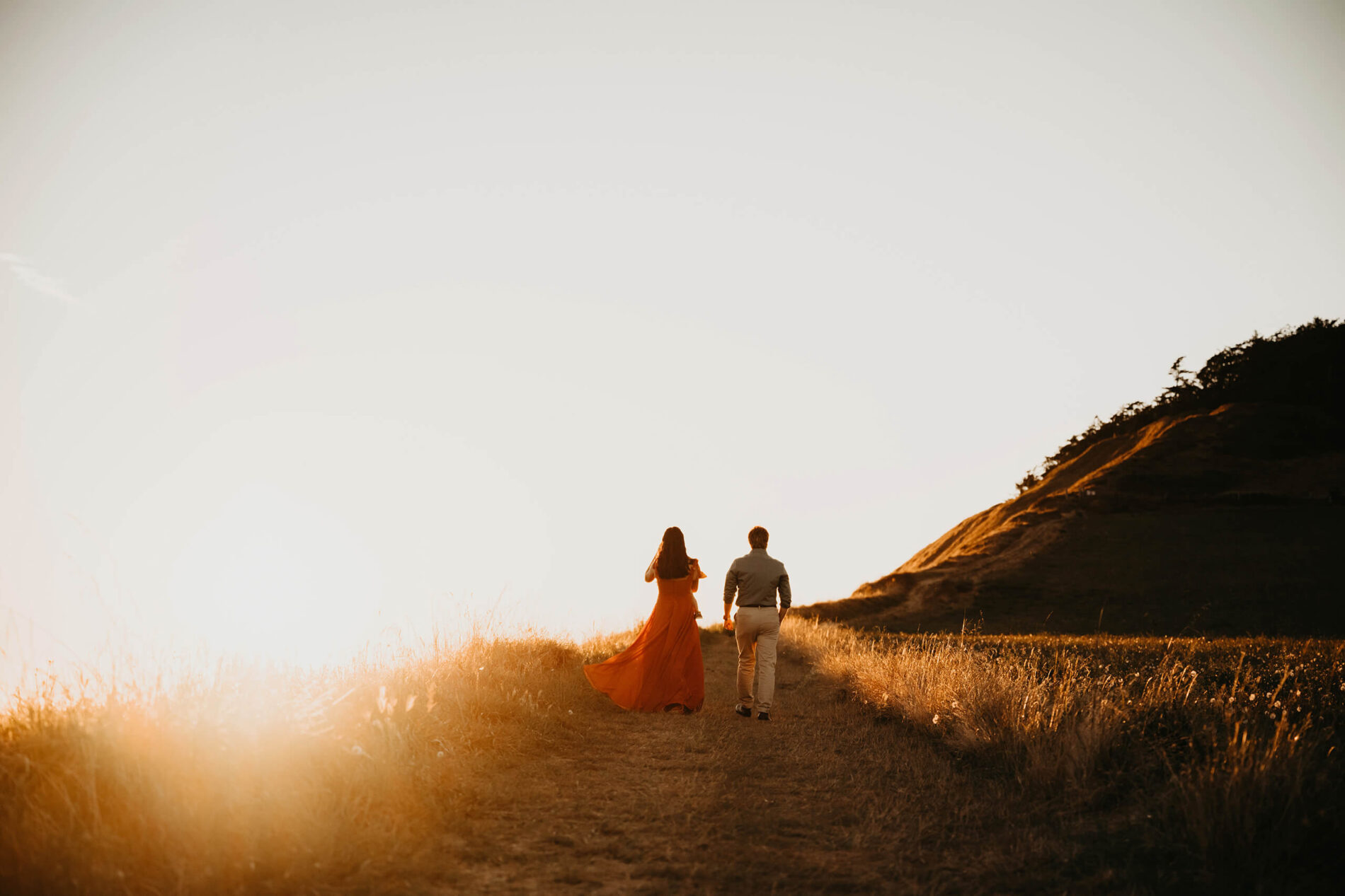 Mom and dad walking with their toddler girl in a meadow at Whidbey Island, WA