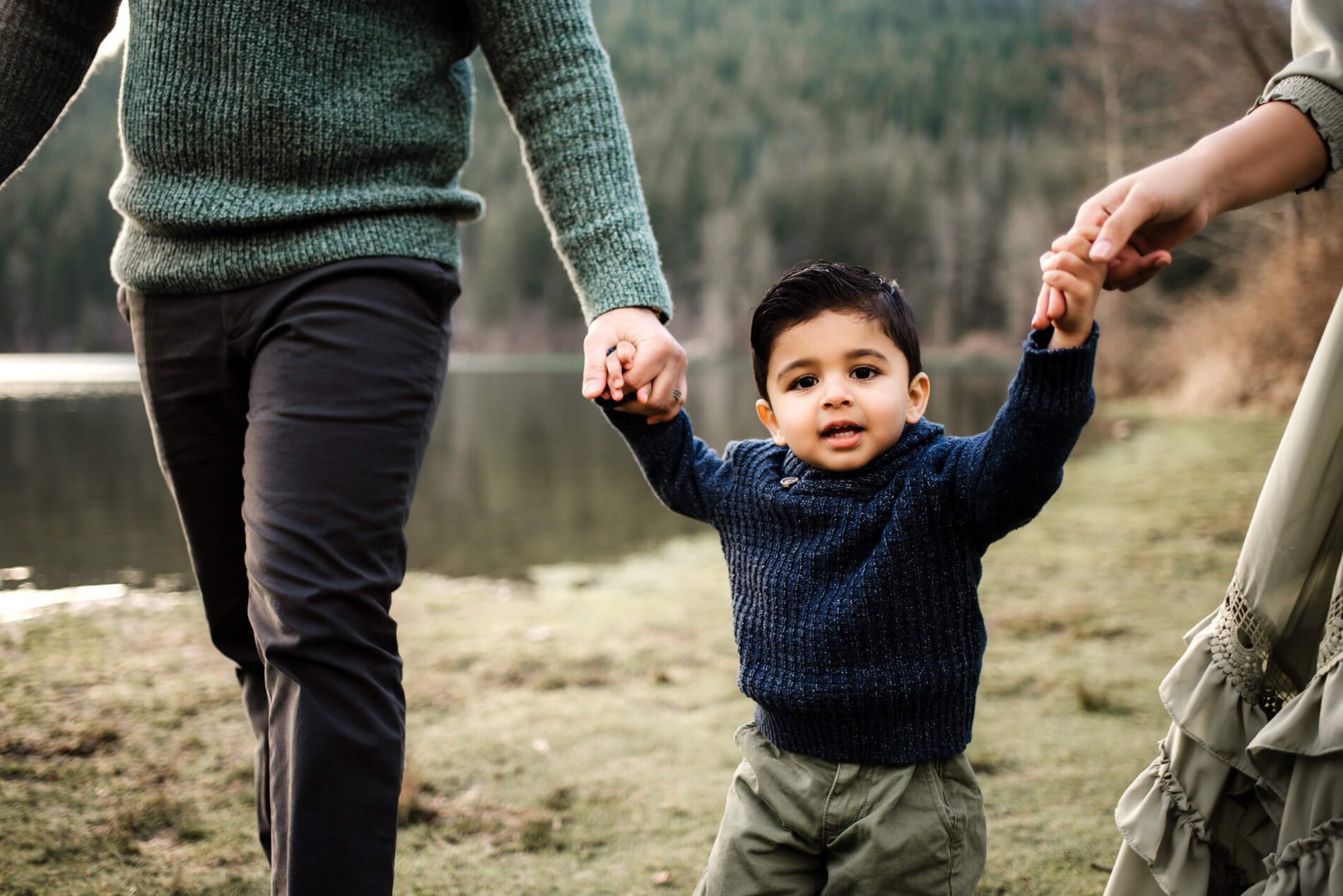Mom and dad holding the hands of their toddler son