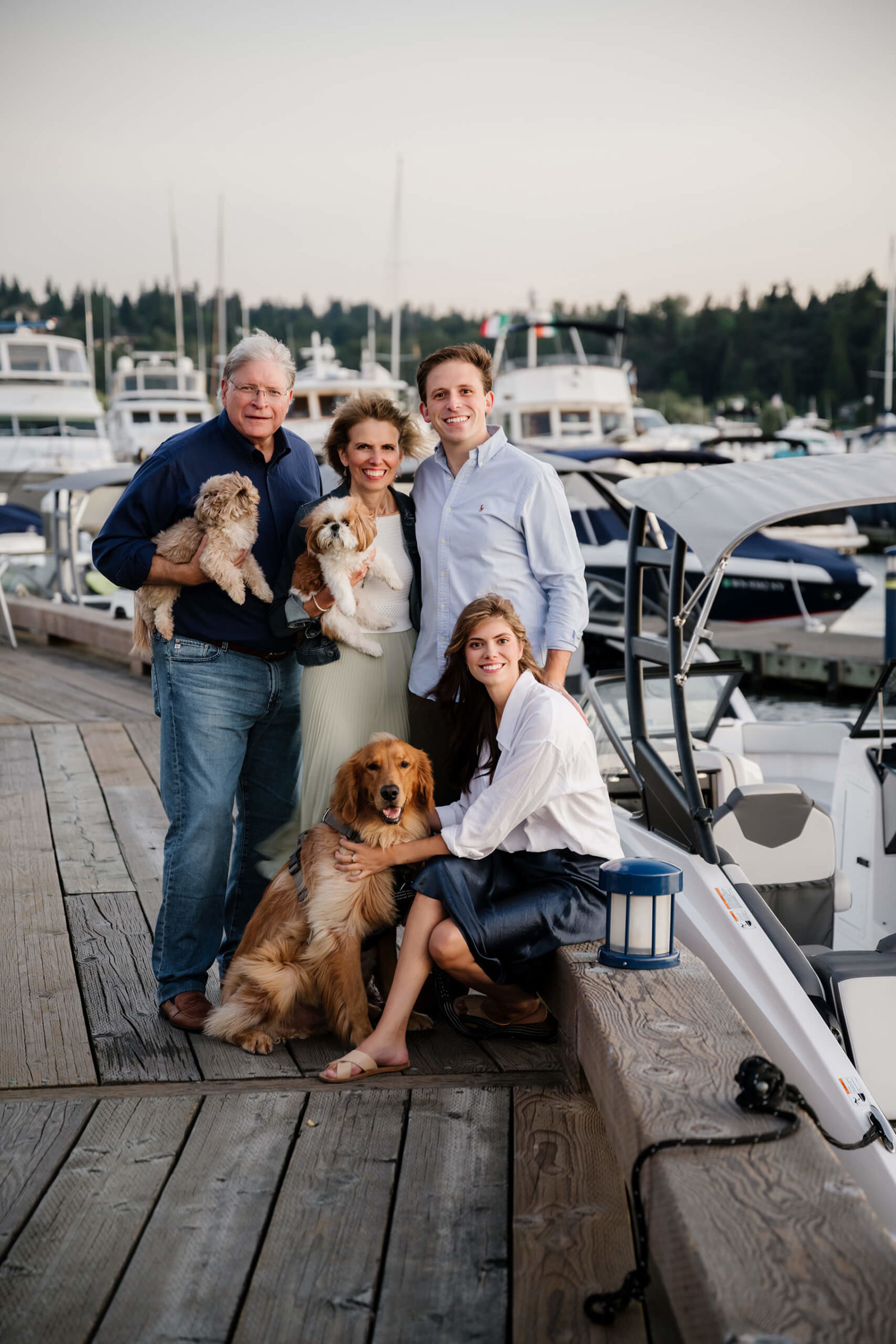 Older husband and wife with their grown-up kids and two dogs posing in a Kirkland Marina
