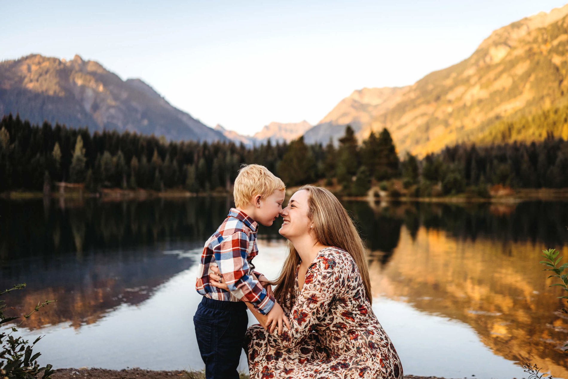 Seattle family photography with mom and her son beside a serene lake with mountains in the background