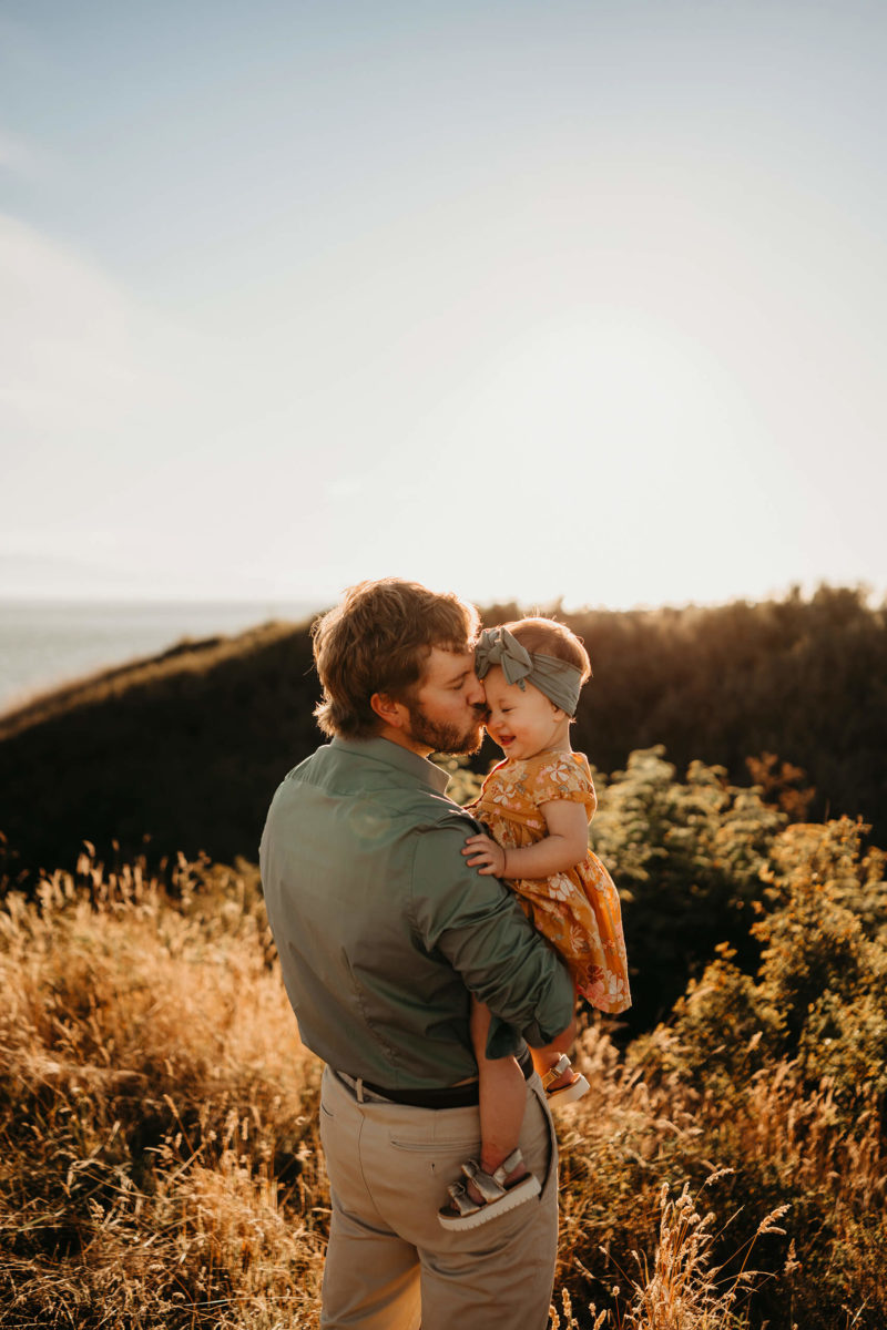 In a sunlit landscape, dad and daughter, playing and having fun during the sunset