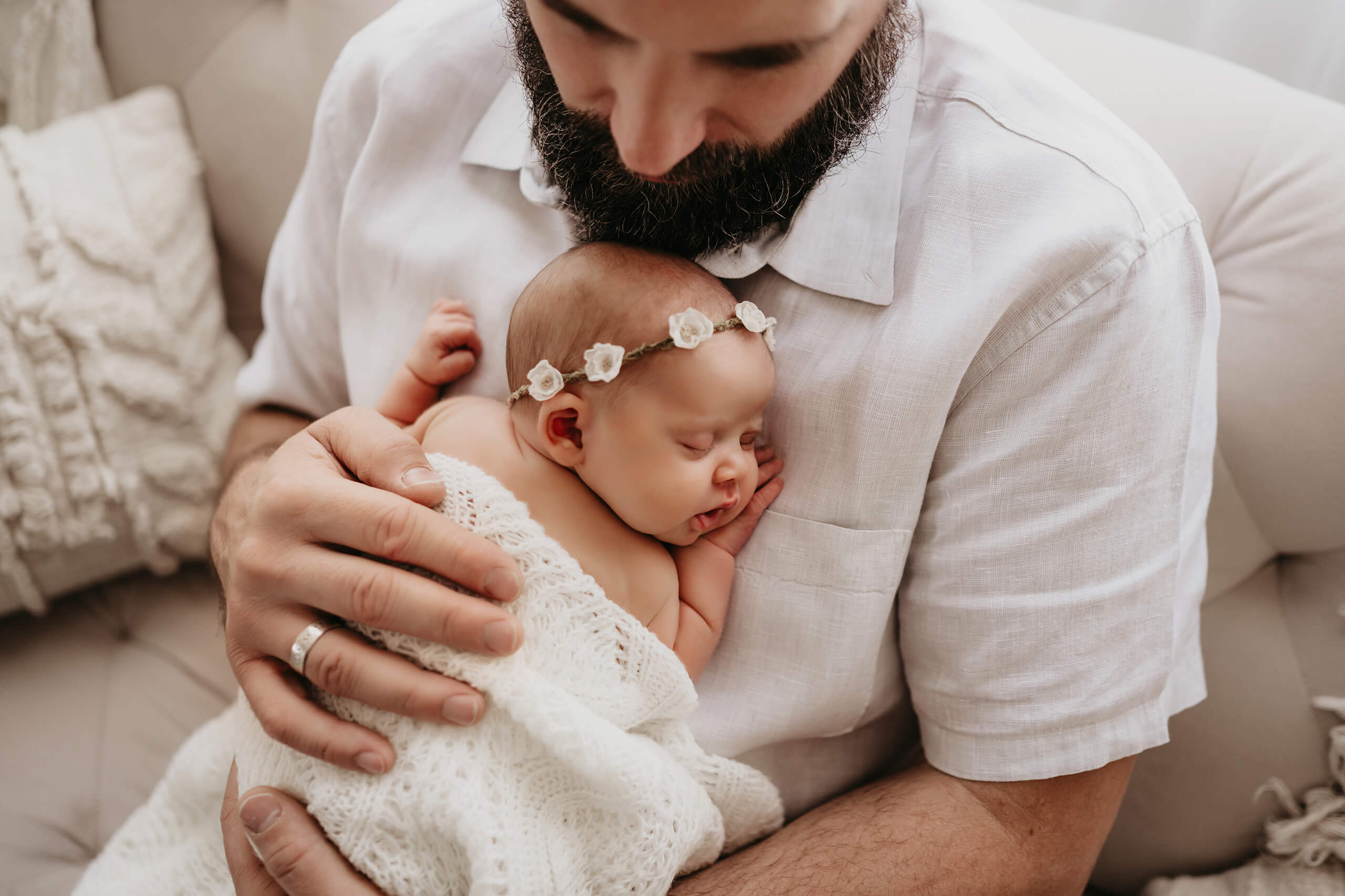 Father holding his sleeping newborn baby during a soft indoor newborn session
