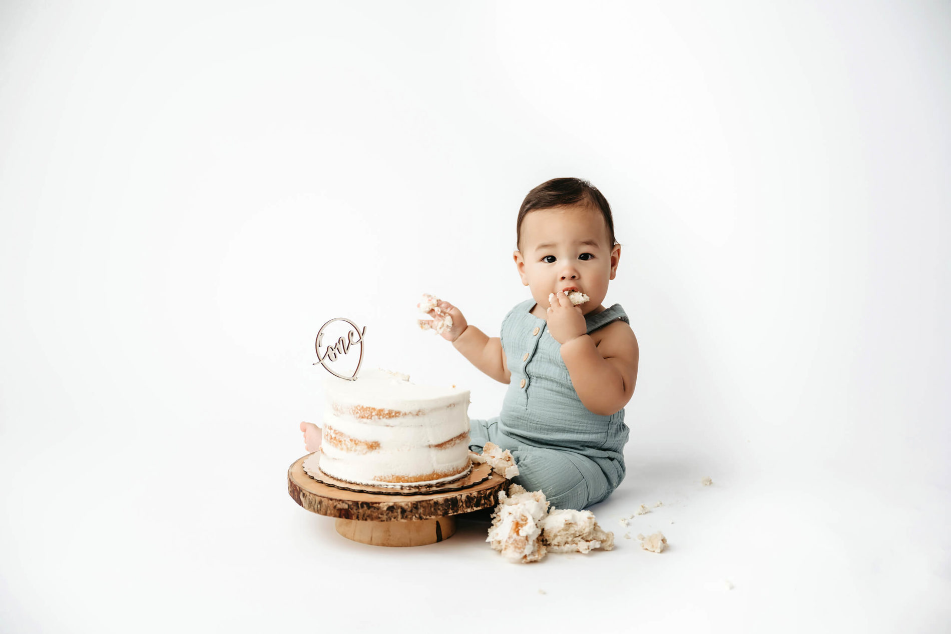 Adorable one-year-old boy exploring a cake on the floor of a photography studio