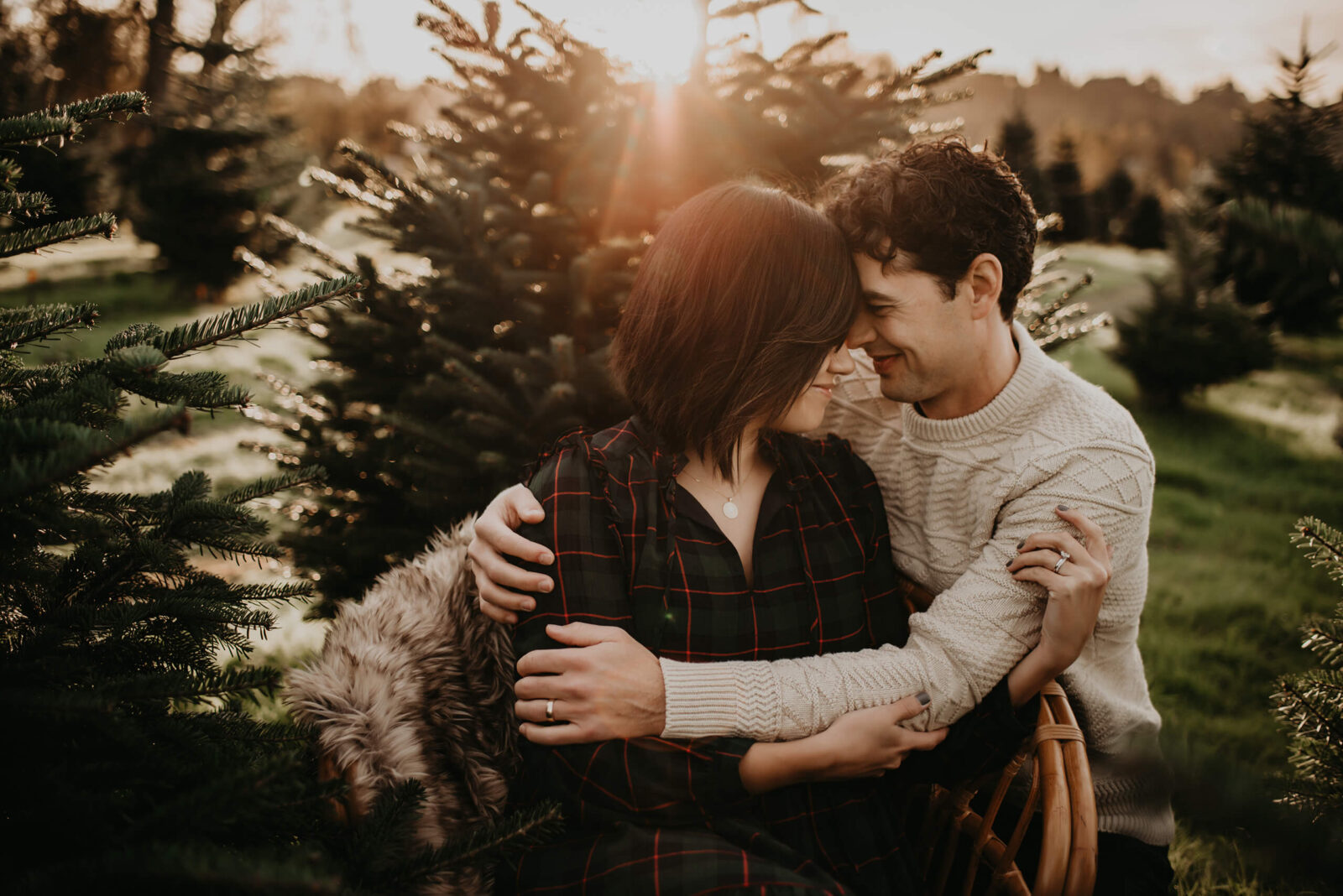 Young couple hugging and smiling during sunset at a beautiful Christmas tree farm