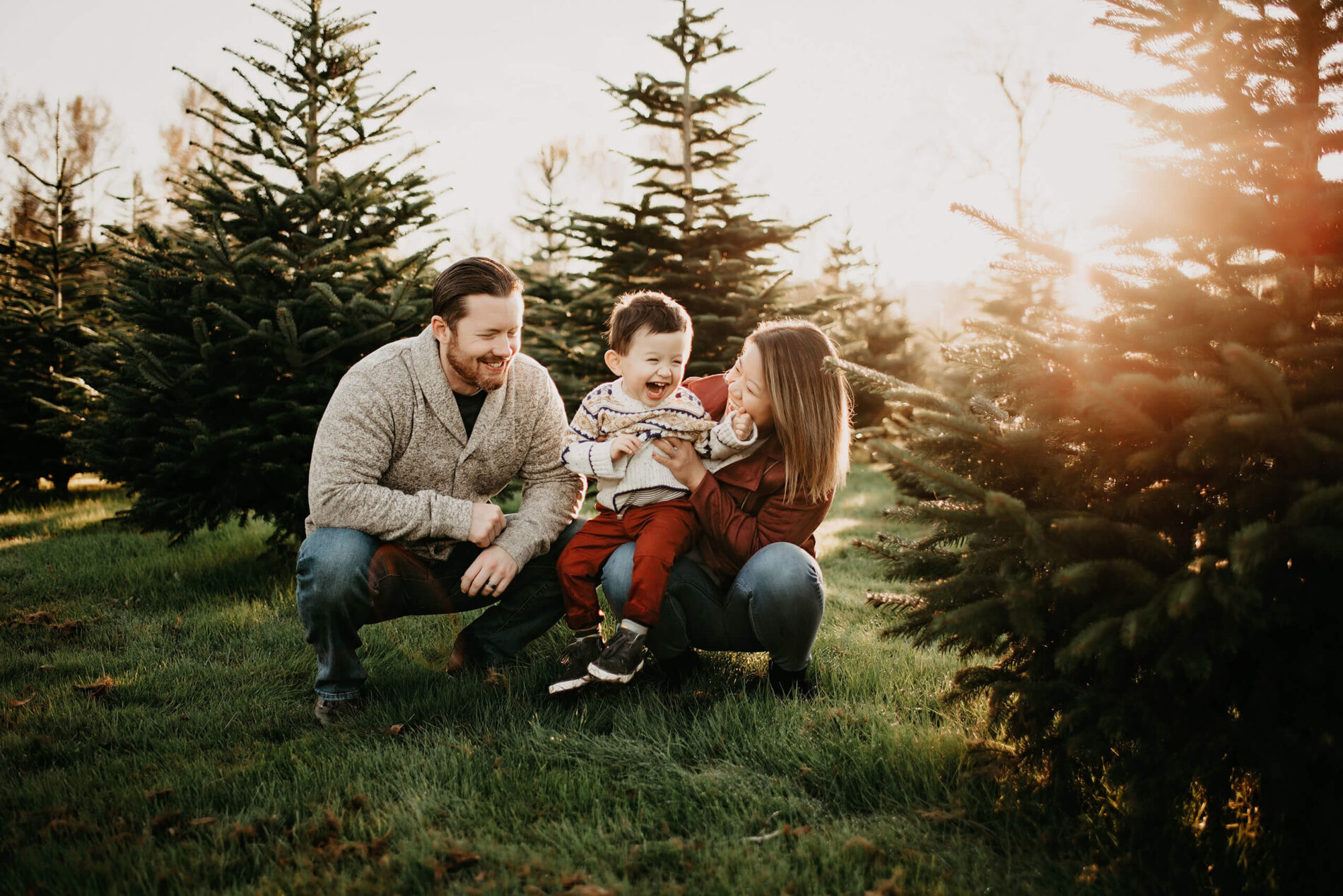 A candid holiday portrait of mom and dad having fun with their son at a Christmas tree farm near Seattle