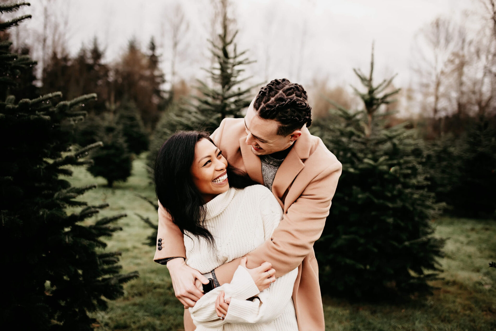 A young couple hugging at a Christmas tree farm