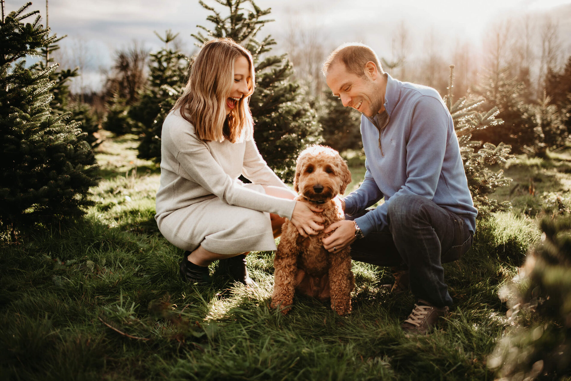 Husband and wife petting their dog at a Christmas tree farm