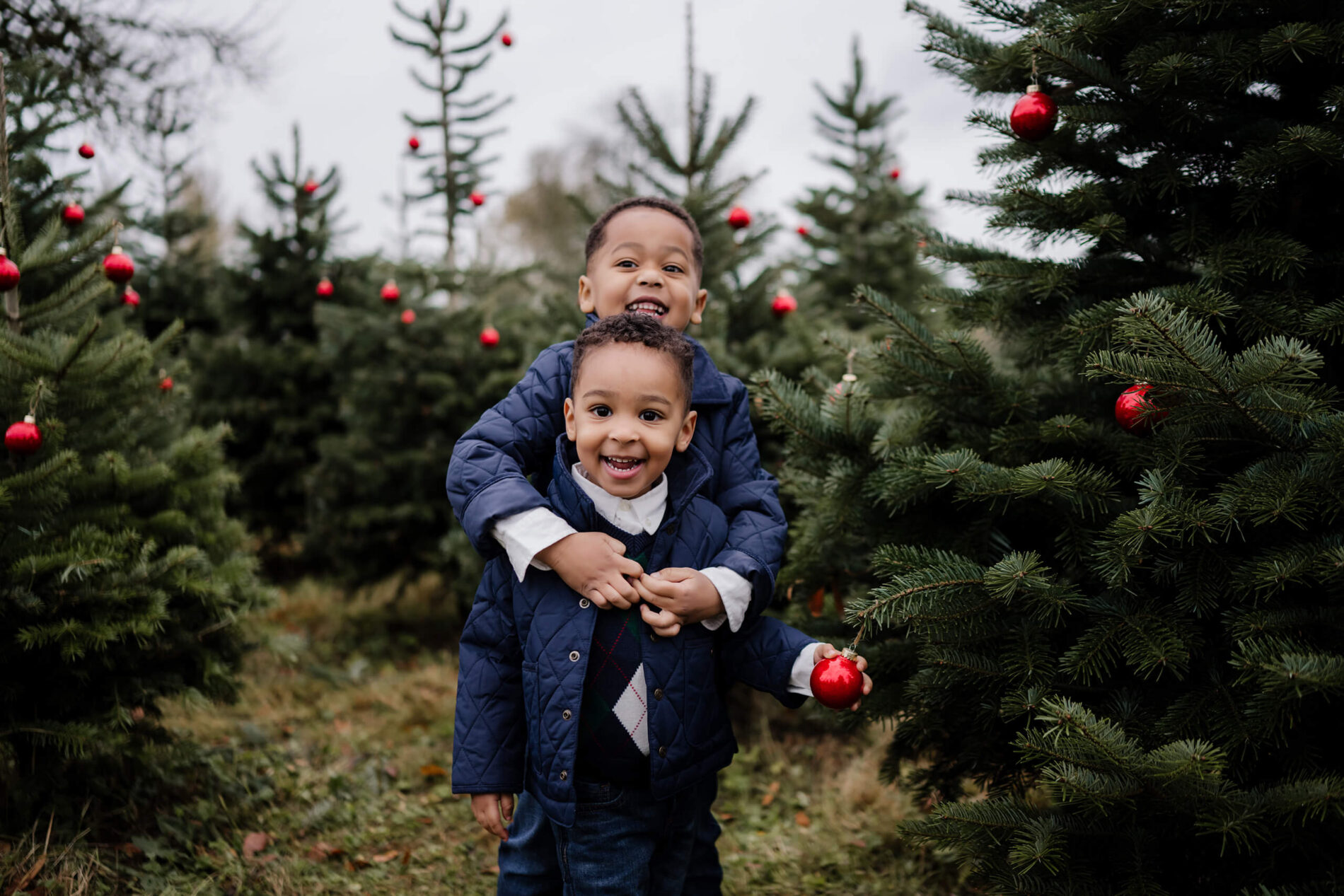 Two brothers hugging at a Christmas tree farm