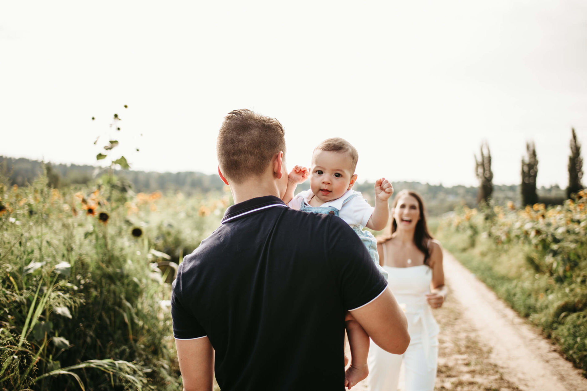 Dad holding his young son with mom smiling in the background