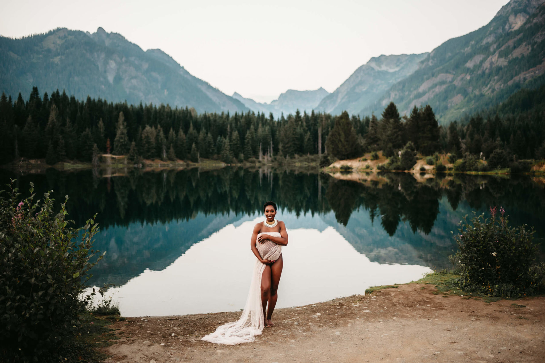 Pregnant woman posing next to a lake during maternity photo shoot