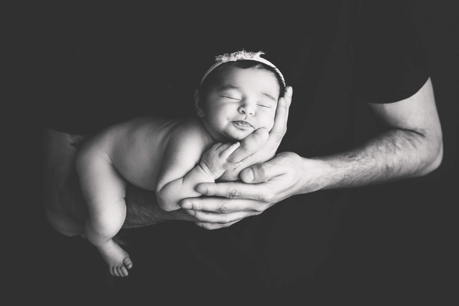 Close-up of a baby girl sleeping peacefully in her dad's arms