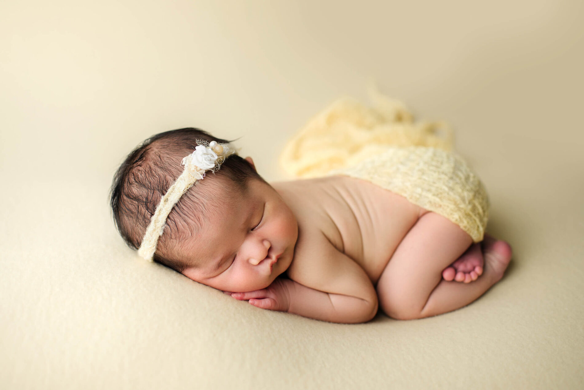 Newborn girl peacefully sleeping slightly covered with a yellow blanket