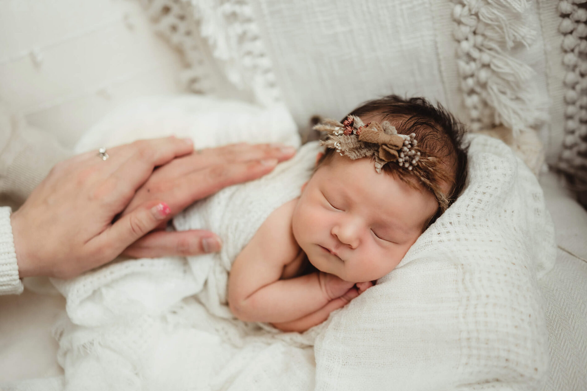 A newborn girl peacefully sleeping, while mom and dad gently have their hands on her back