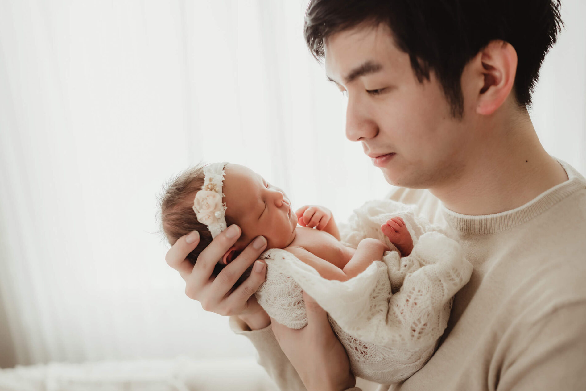 A father holding hew newborn girl close to his face