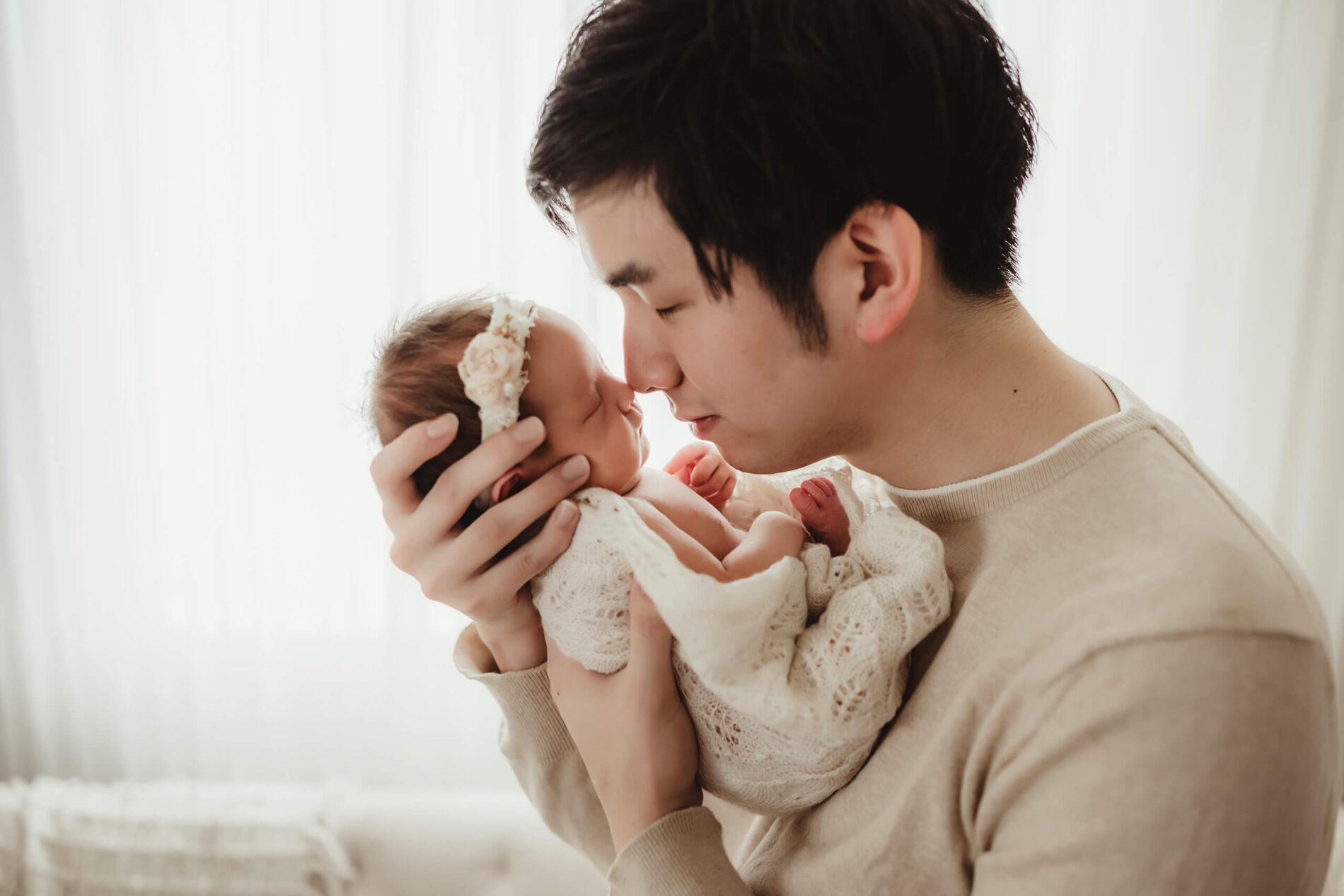 A father holding his newborn daughter close to his face, kissing her