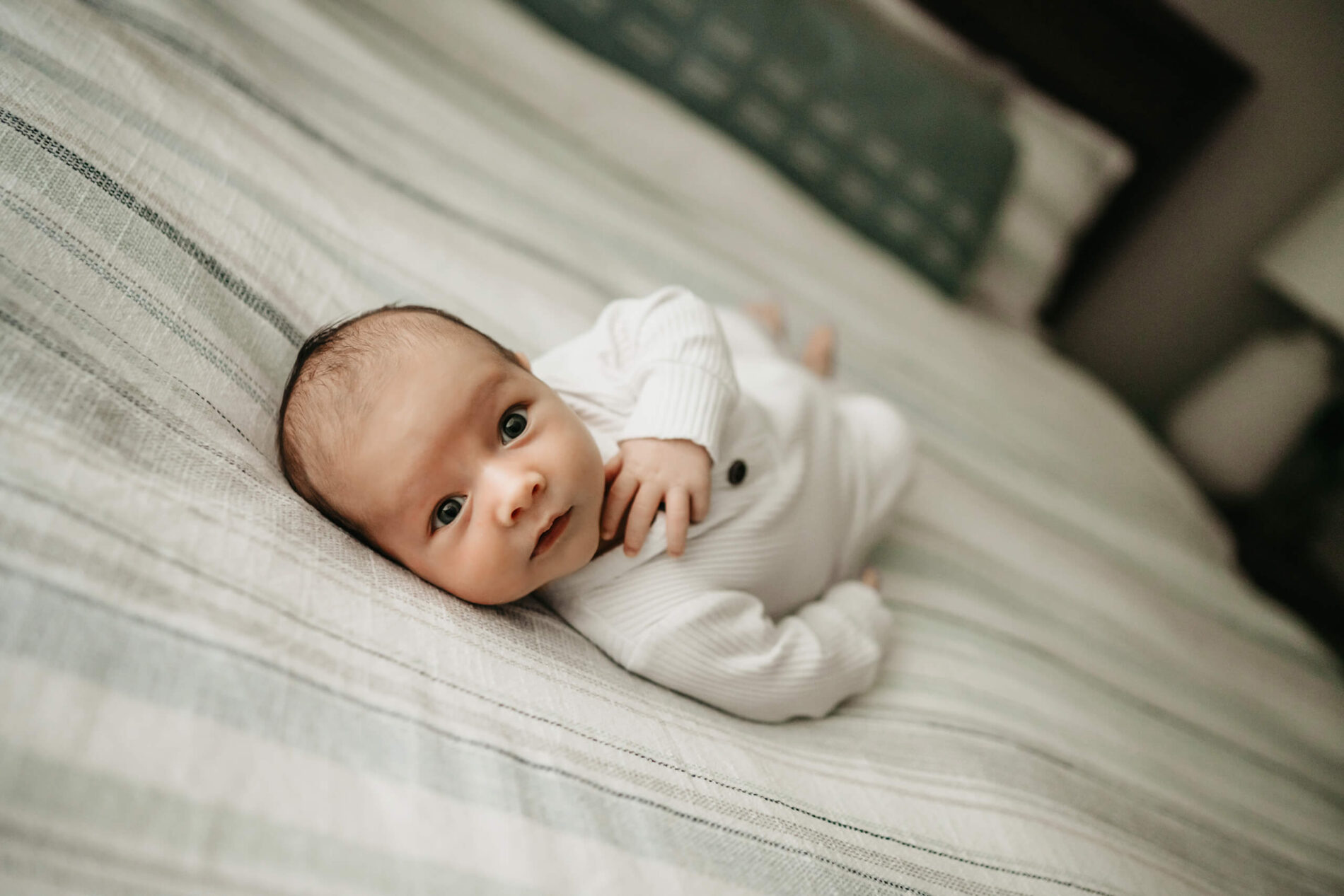 A close-up on an awake happy newborn boy lying on parent's bed