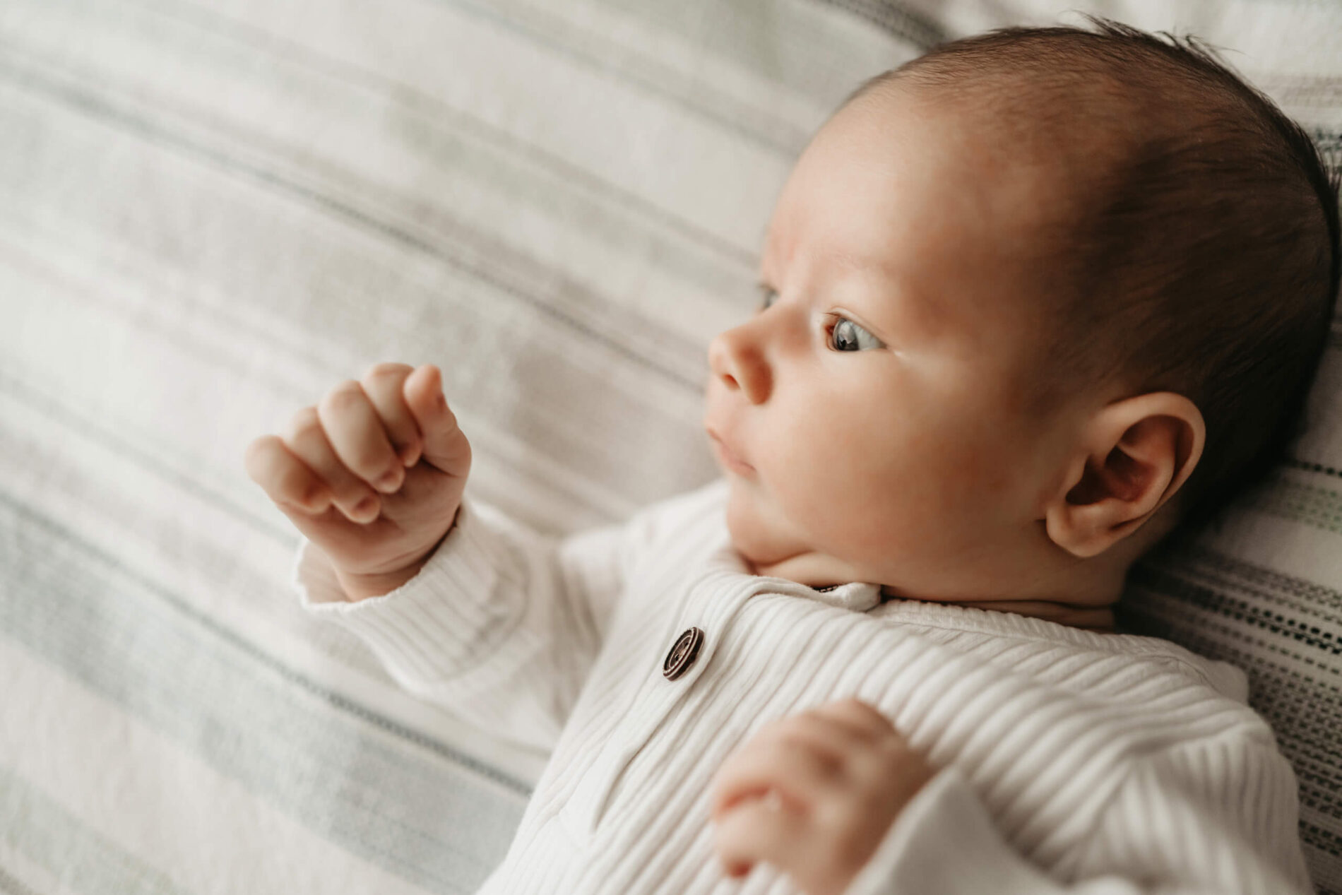 A close-up on newborn boy's face looking into the window