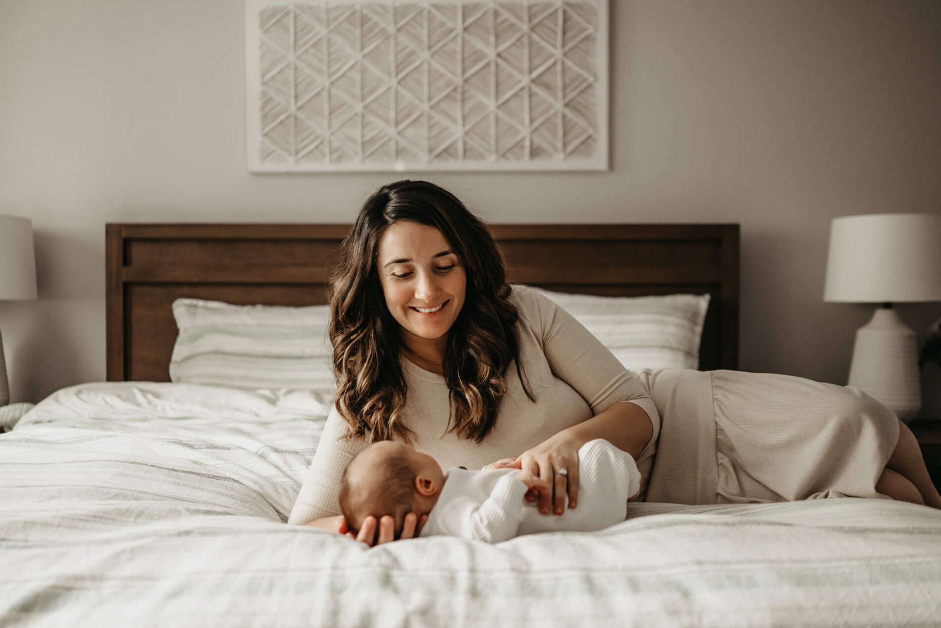 Mom lying on her bed, interacting with her newborn son