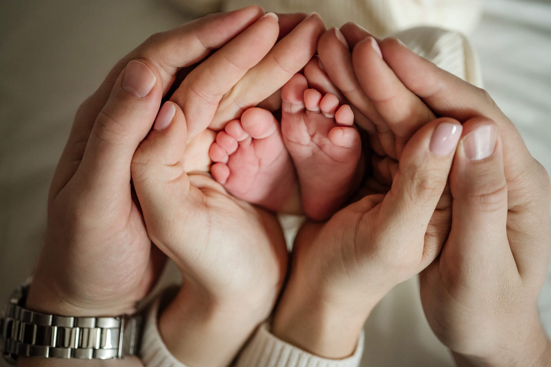 A close-up of mom and dad's hands wrapped around newborn daughter's feet