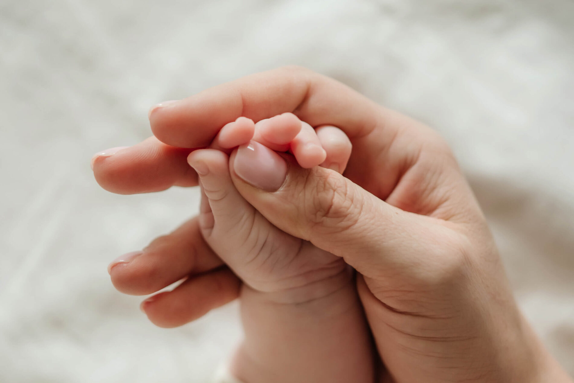 A close-up of mom's hand holding her newborn daughter's hand