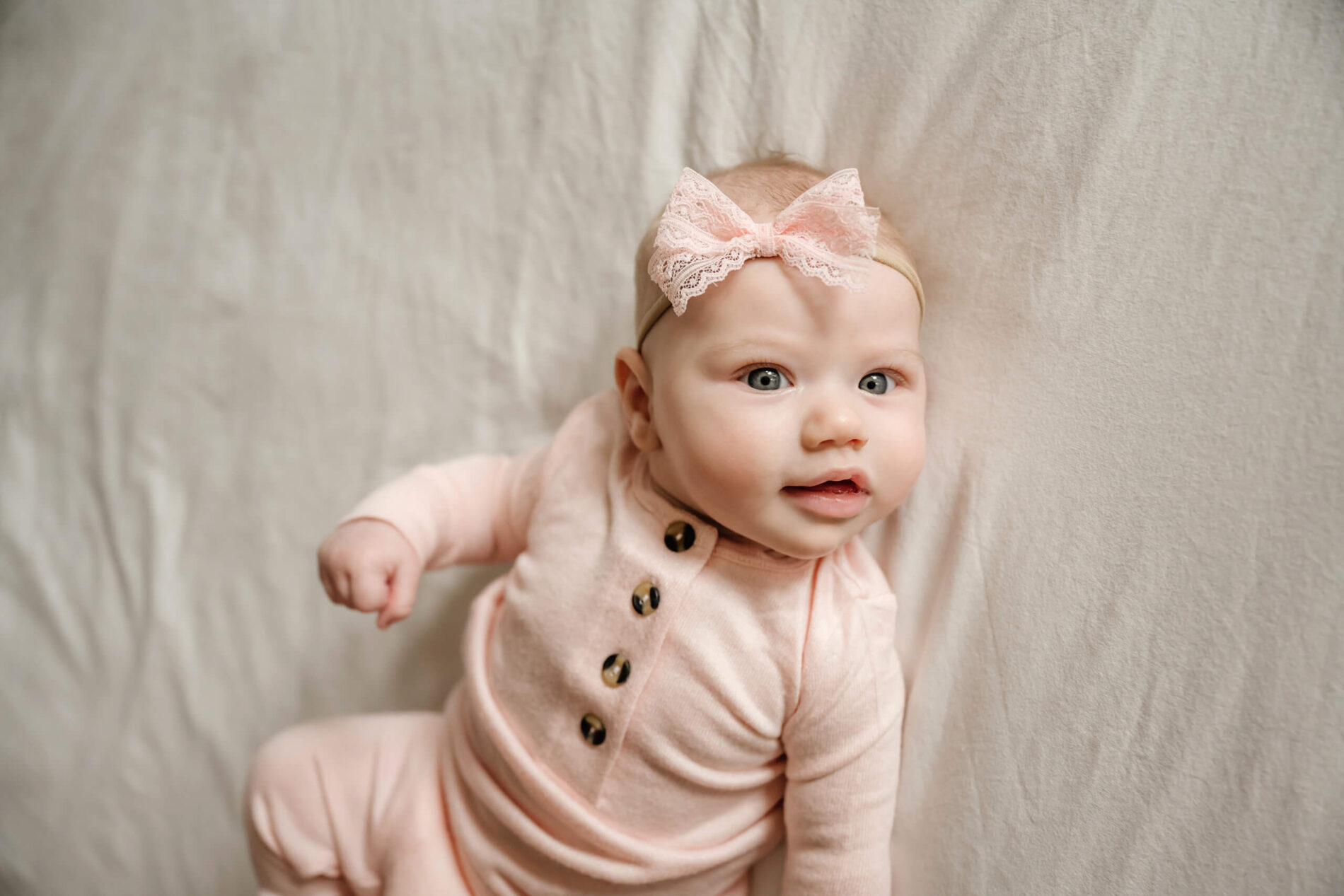 A cute newborn girl smiling and lying on her parent's bed