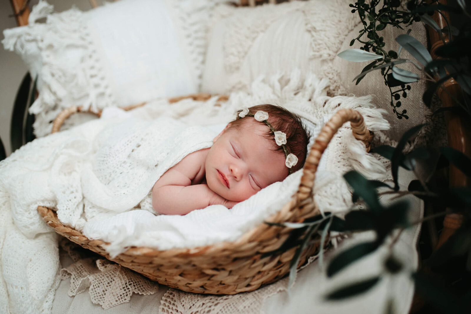 Newborn girl sleeping in a basket under white covers