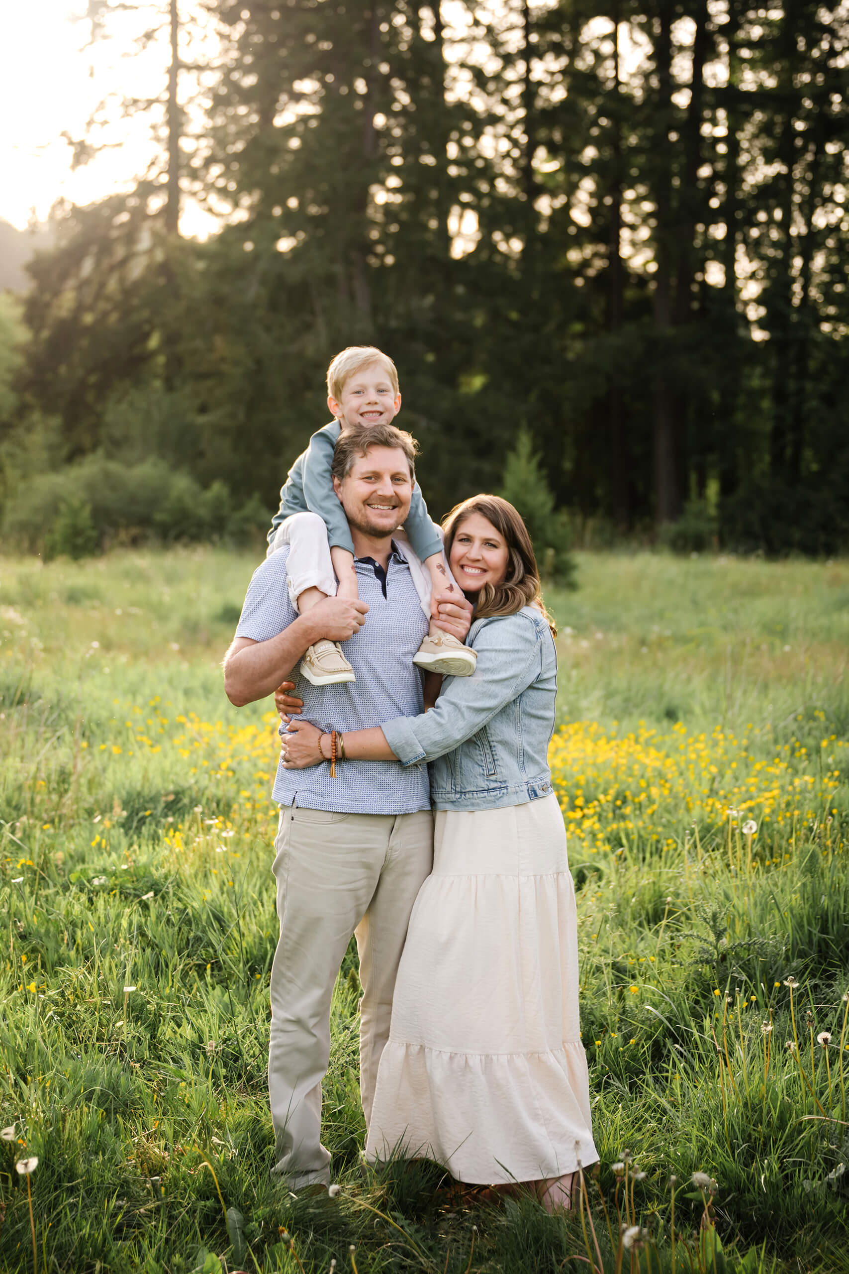 Family of three standing together in a field of yellow wildflowers during an outdoor family session.