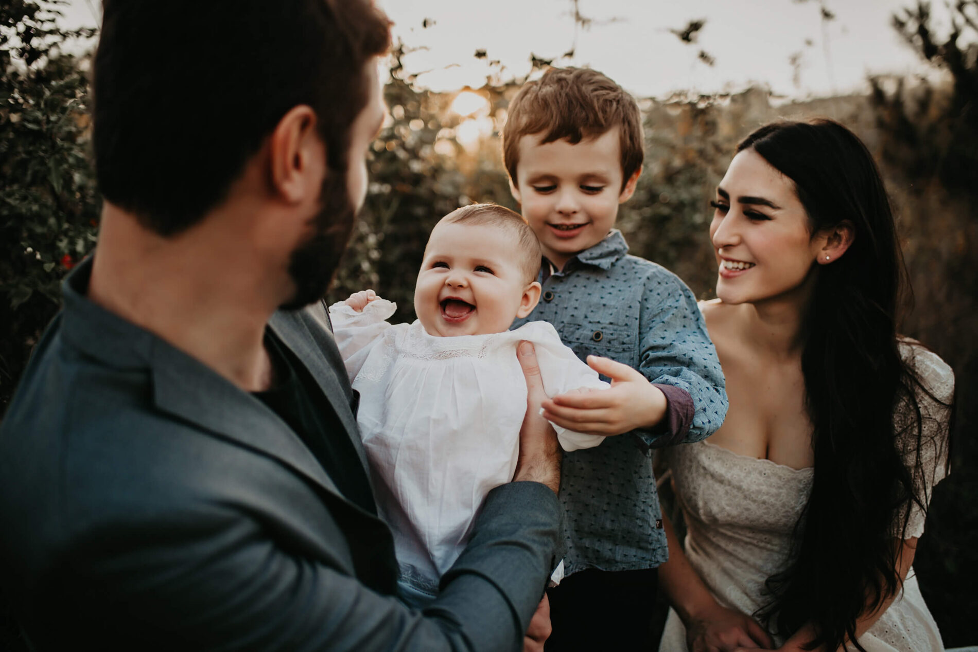 Family photo shoot in Seattle, one year old girl smiling at her dad while her mom and brother are looking on