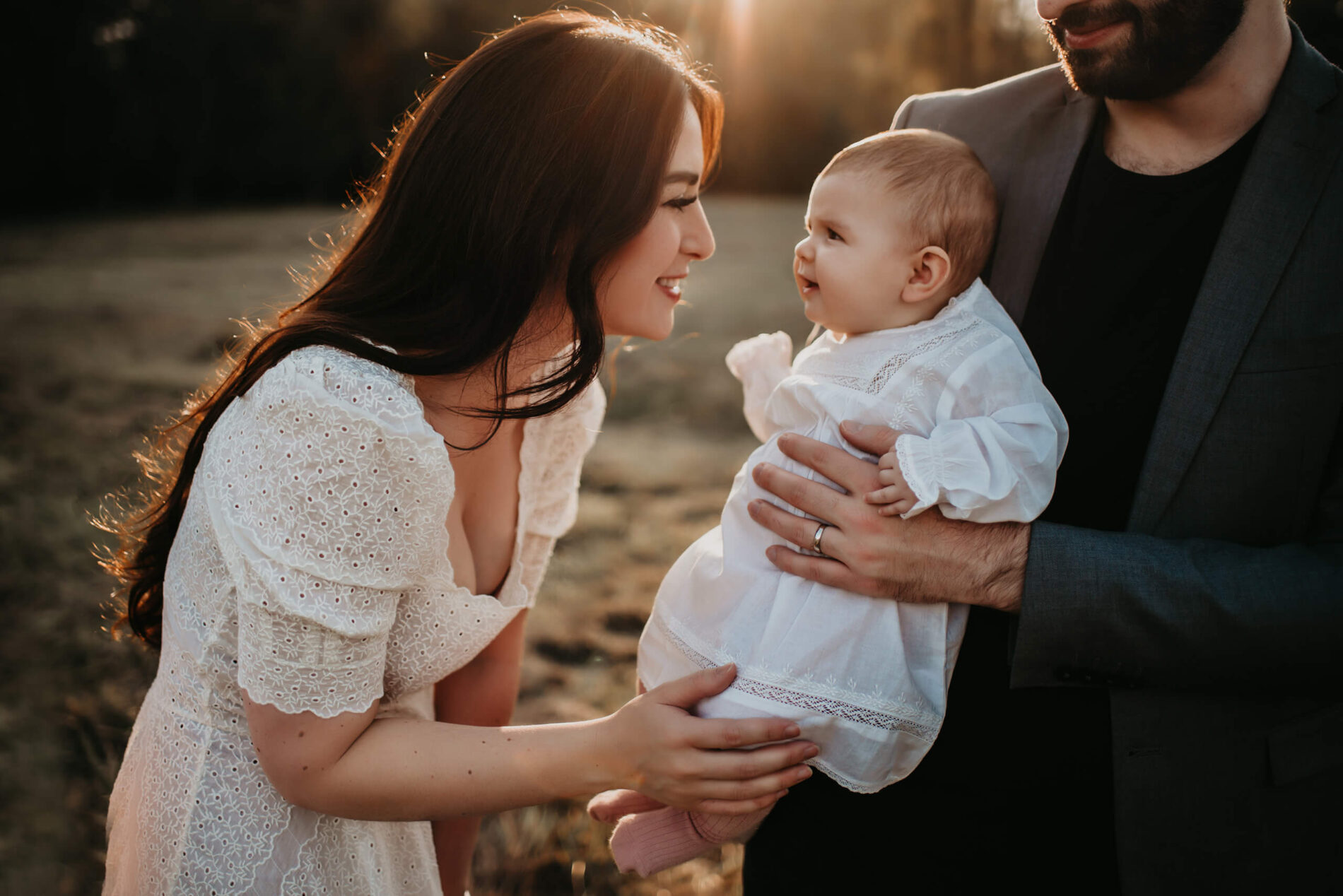 Family photo shoot in Seattle, mom and young daughter smiling, with dad in the background