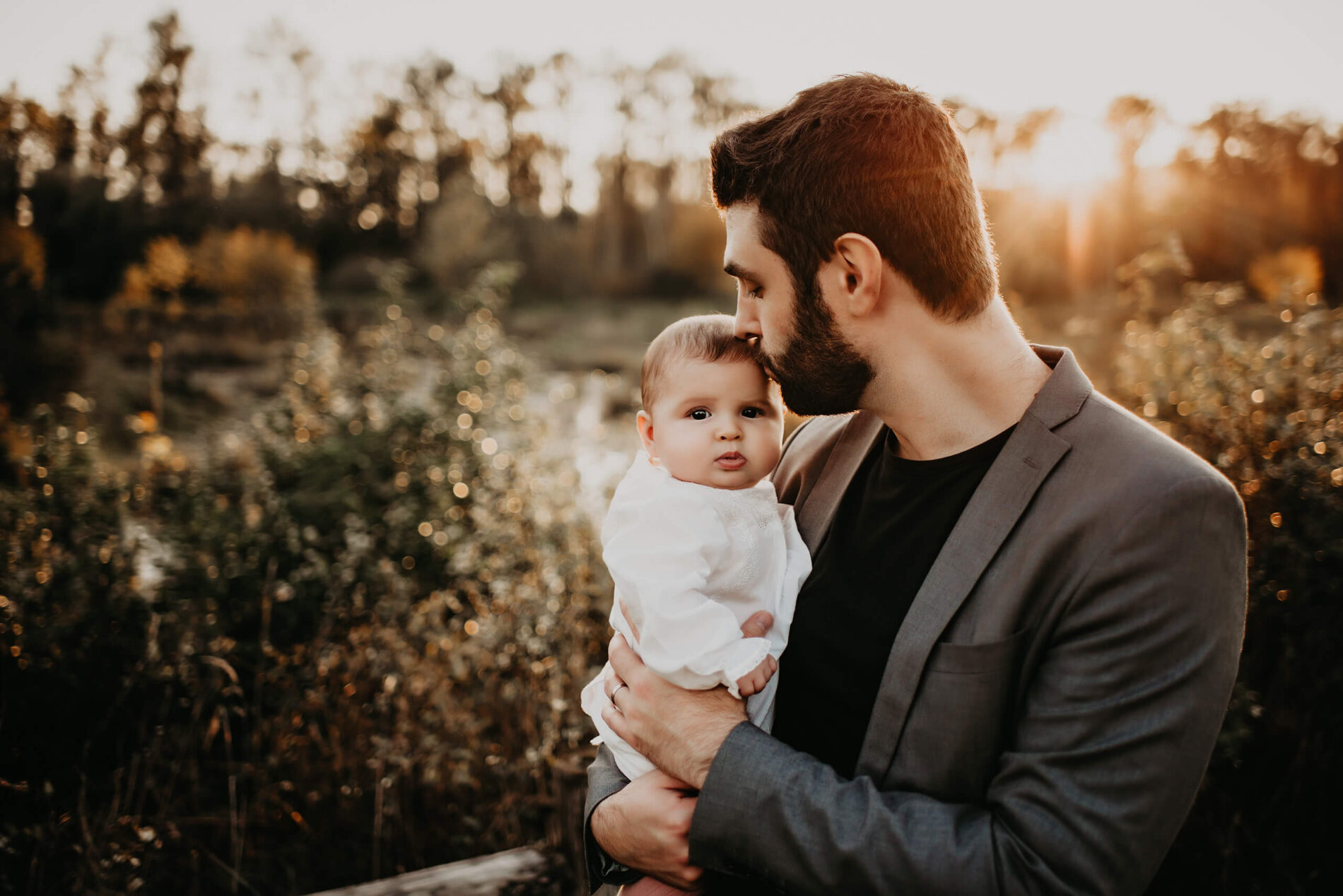Family photo shoot in Seattle, dad gently kissing his daughter's head during sunset