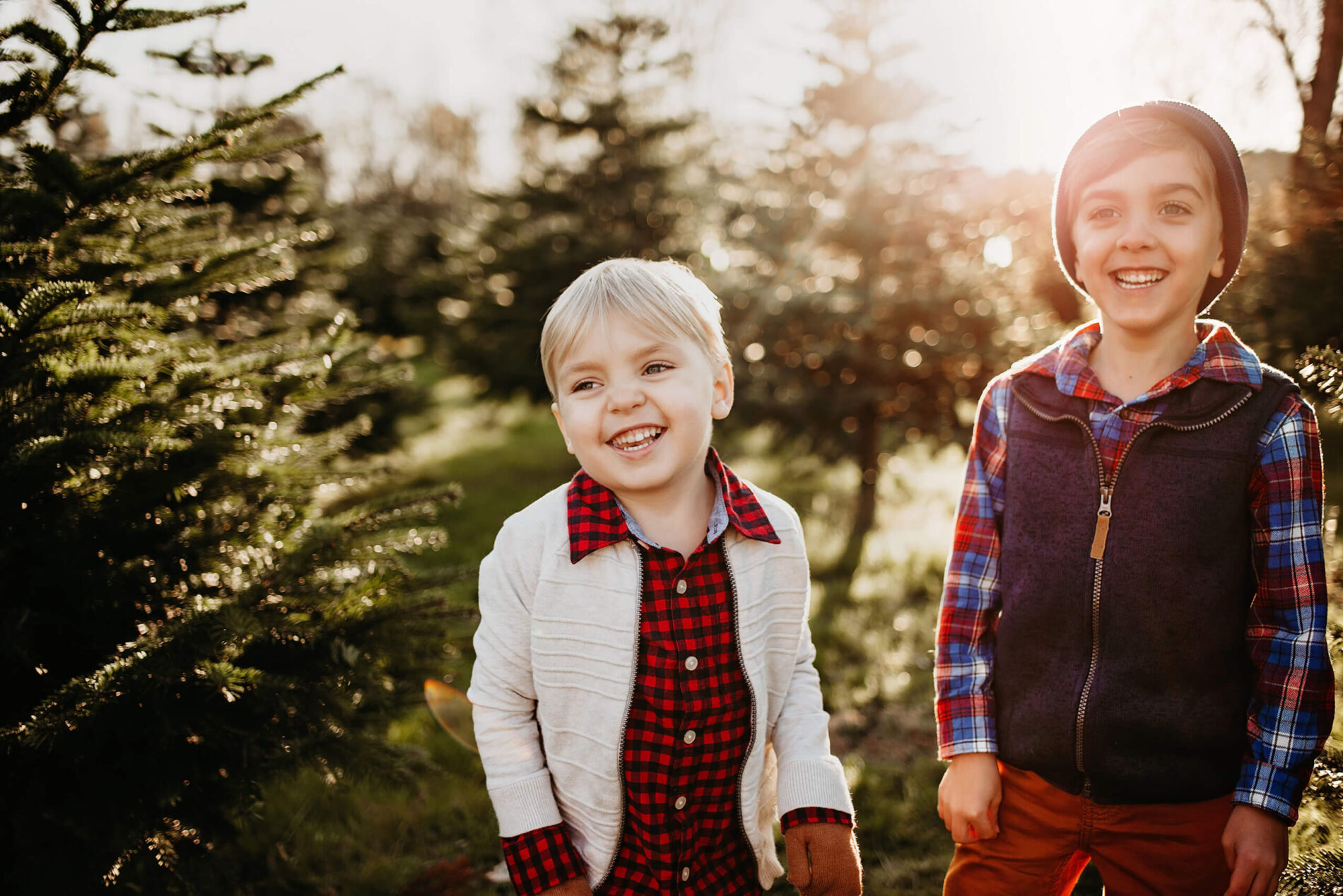 Two brothers smiling and having fun at a Christmas tree farm