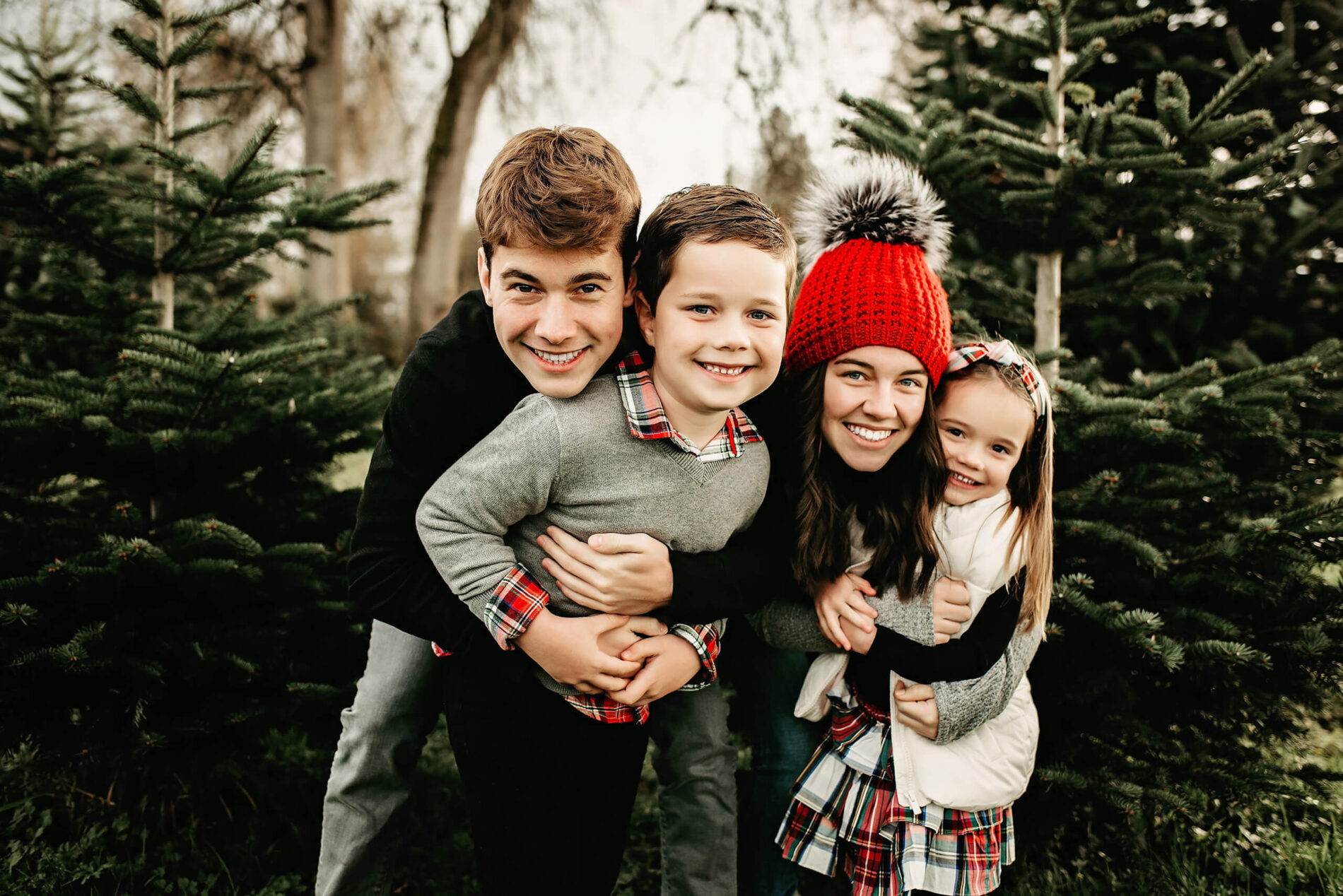 Two brothers and two sisters hugging and smiling at a Christmas tree farm in Redmond, WA