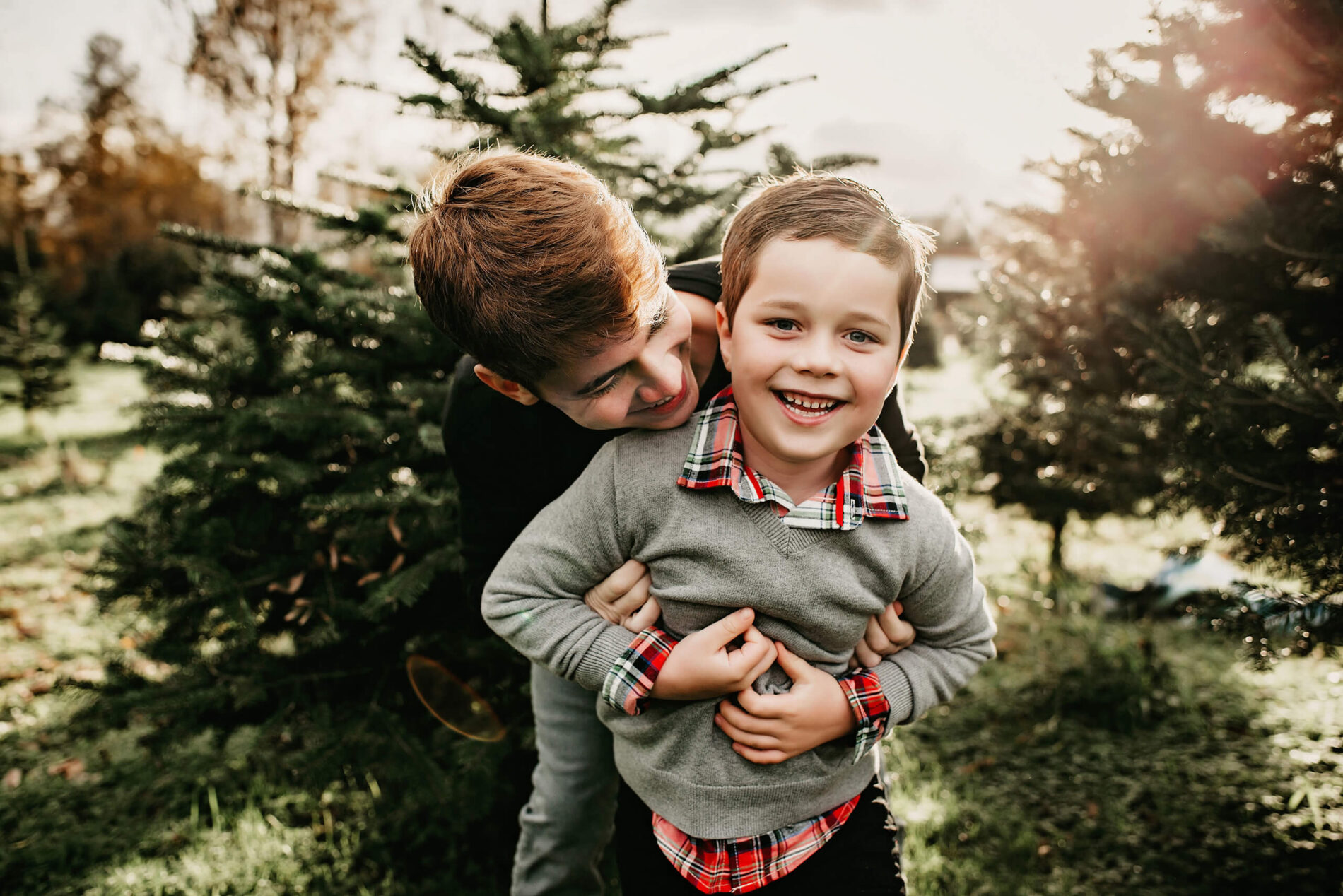 Older brother hugging his younger brother at a Christmas tree farm
