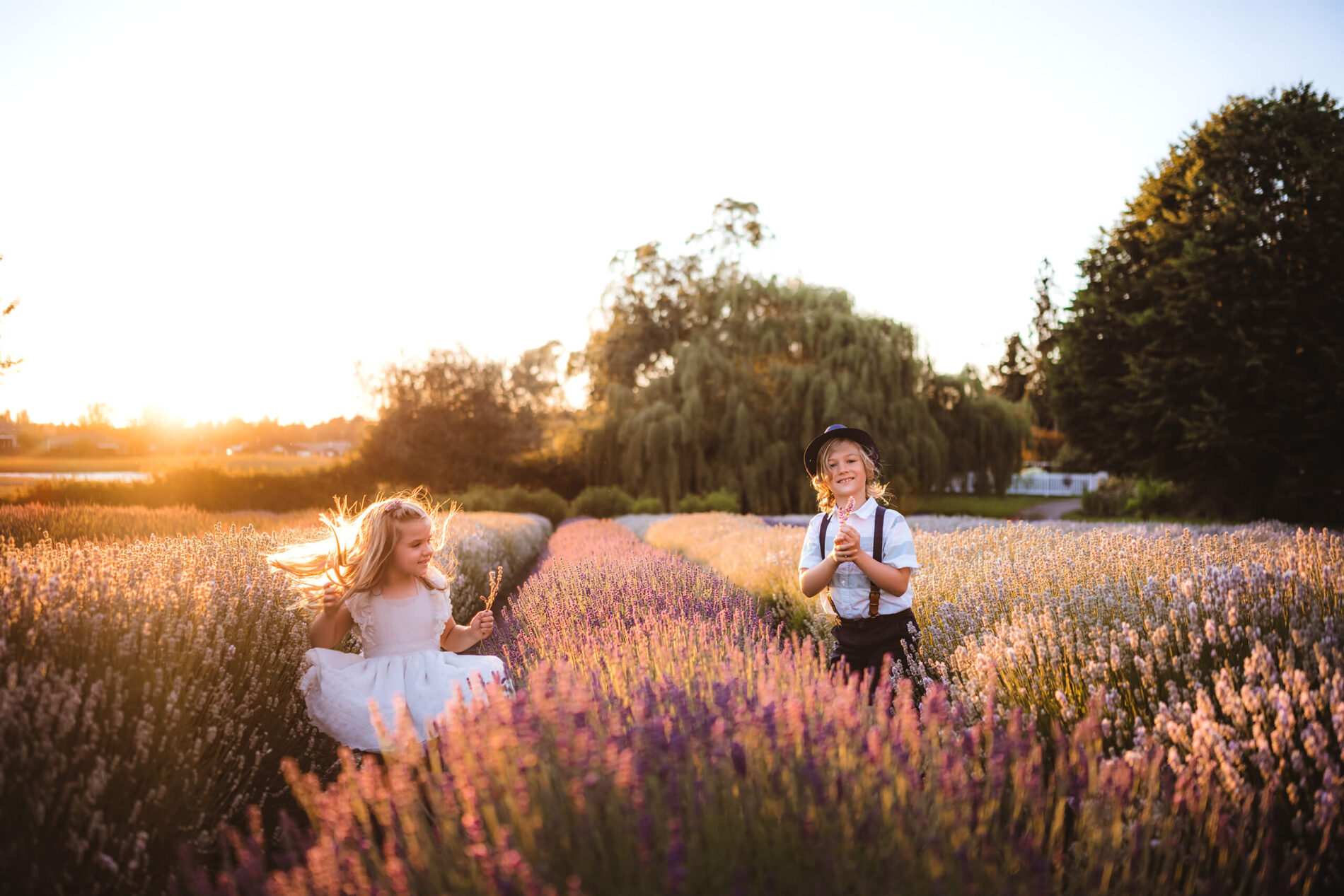 A girl twirling in a lavender field with her brother near by