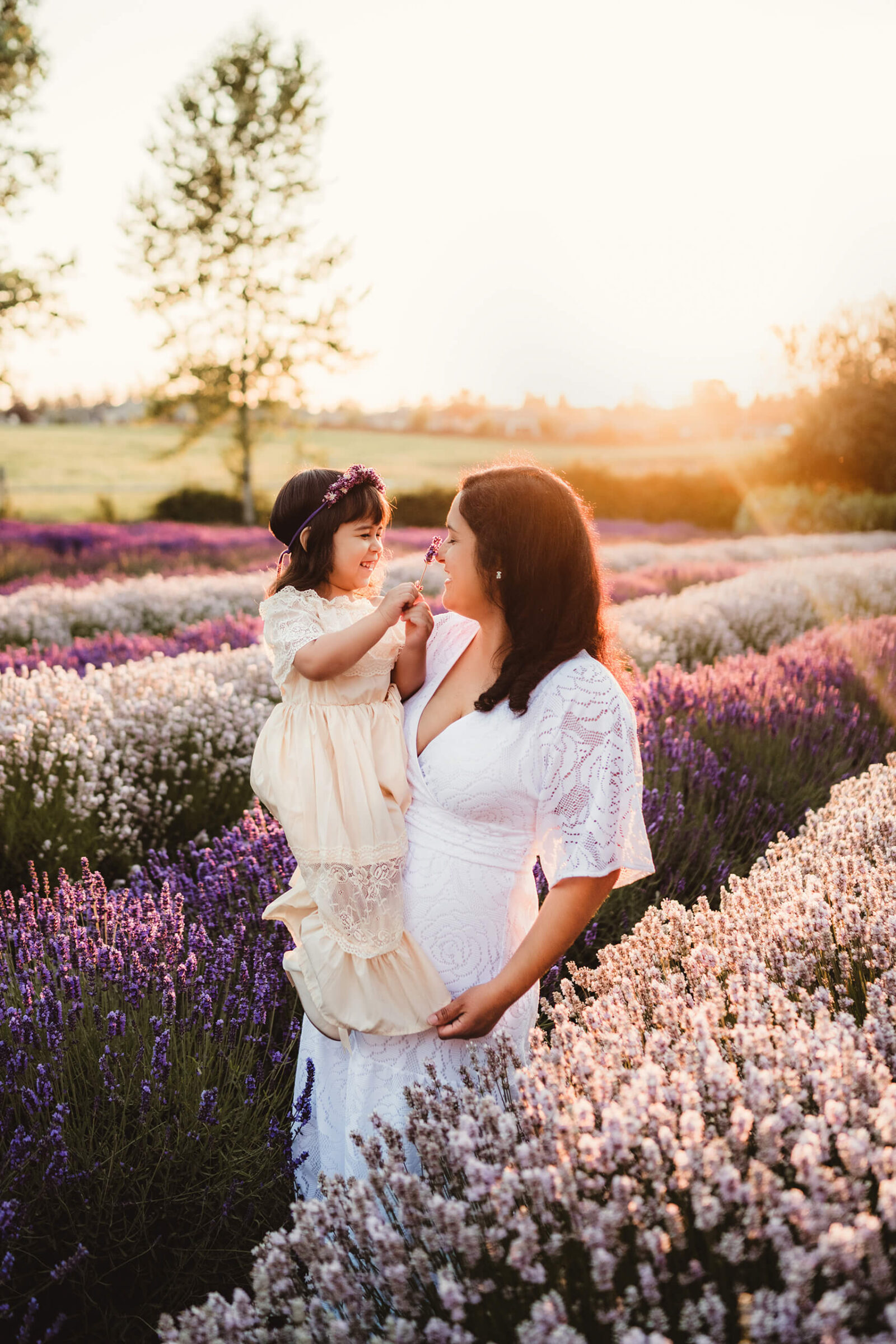 Mom holding her daughter, both smiling, beautiful lavender flowers all around