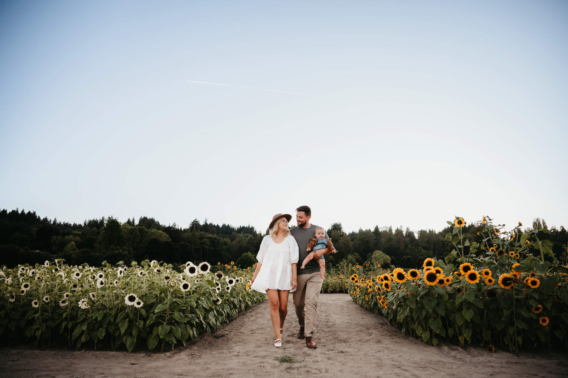 Seattle family photography, mom, dad, with their son walking through a sunflower field in Woodinville, WA