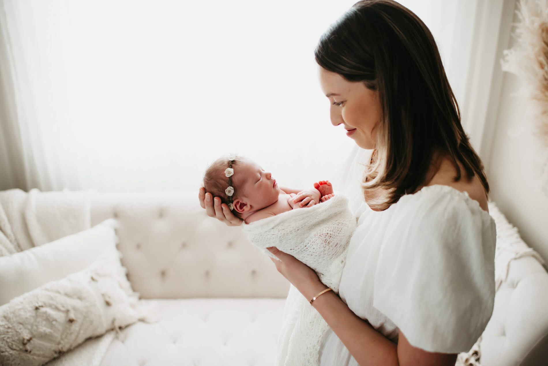 A smiling mom holding her newborn daughter and lovingly looking at her