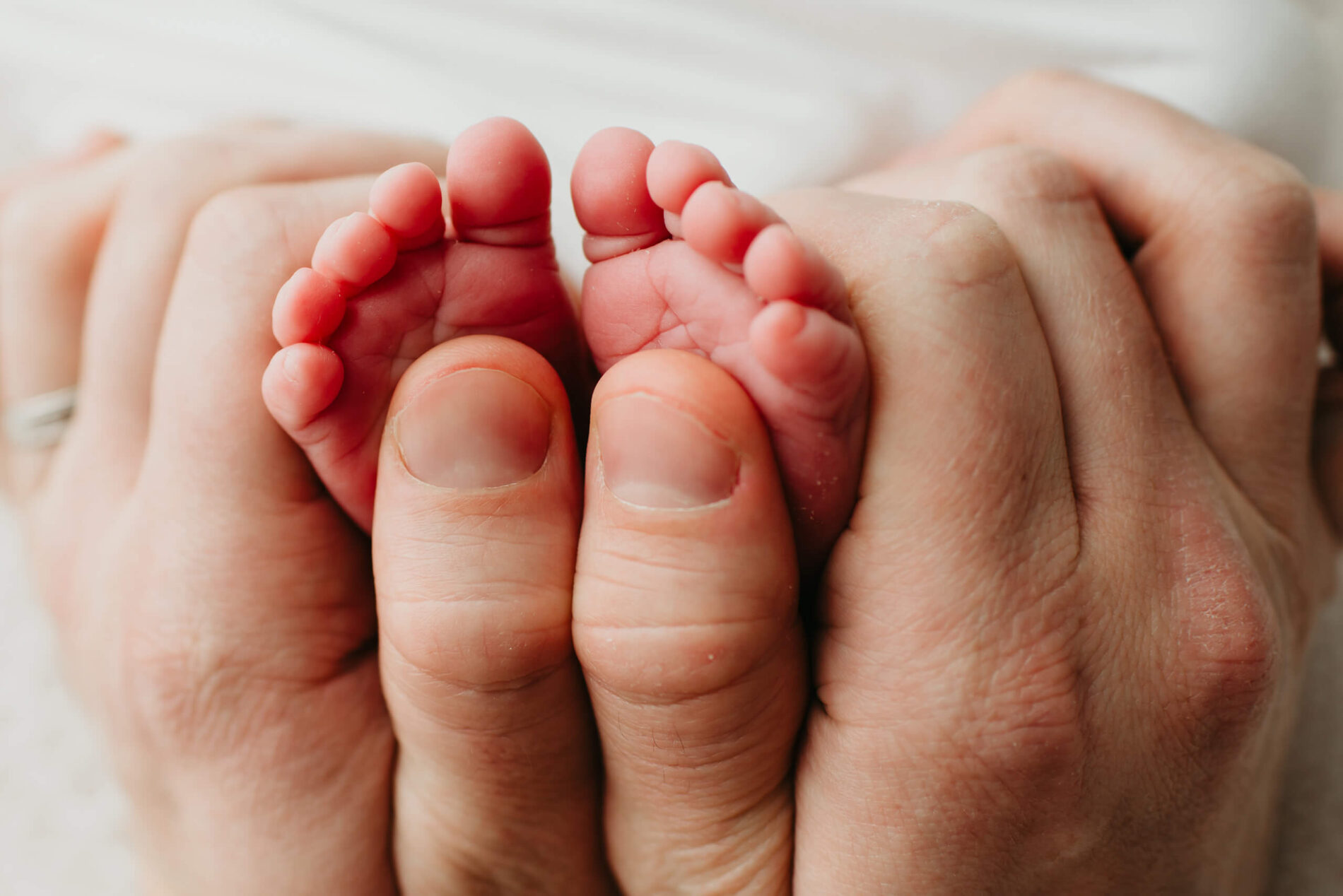 A close-up of father's hands wrapped around newborn's tiny feet