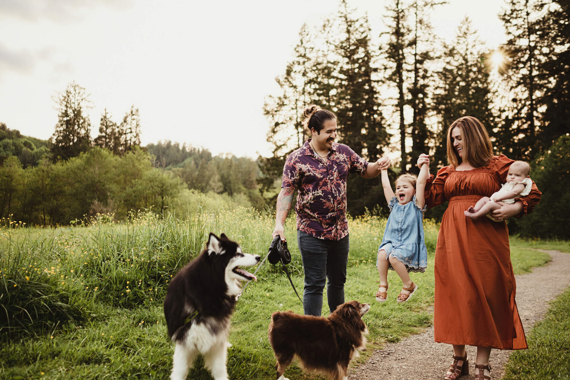 A family of four walking through a field in the park with their two dogs during Seattle family photo session